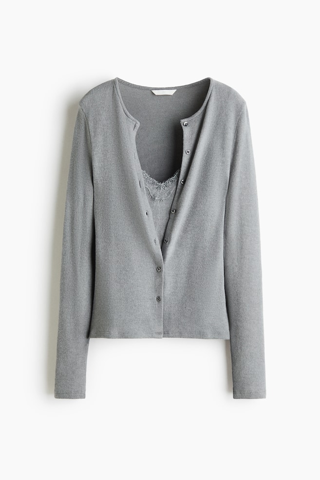 A grey knit cardigan is shown front-on, featuring a round neckline, long sleeves, and a button-fastening front. The cardigan has its top buttons undone, revealing a matching grey lace-trimmed inset. - 1