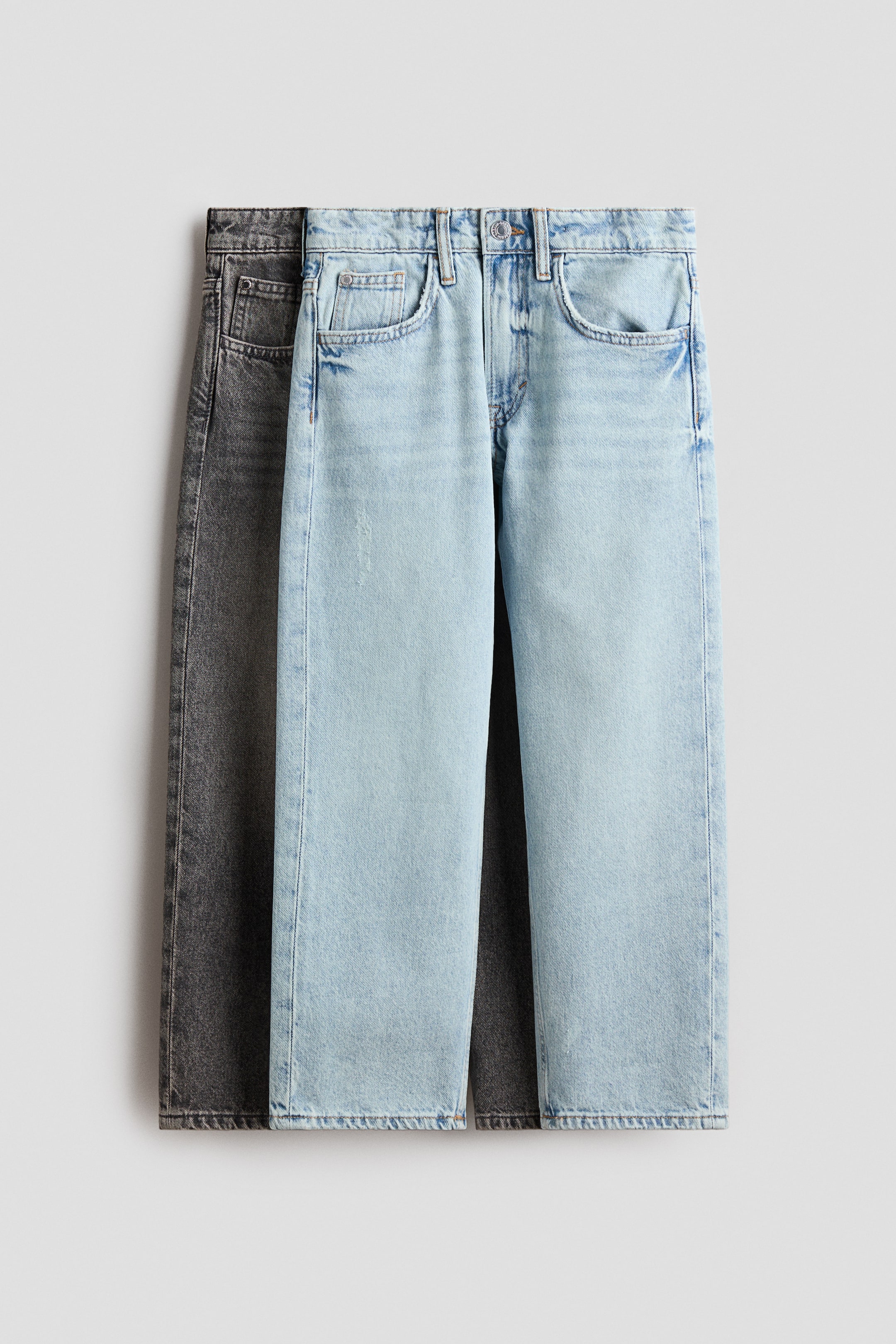 Grotere afbeelding bekijken: Twee paar 5-pocket-jeans van gewassen katoendenim worden vanaf de VOORKANT getoond en hebben een losse pasvorm met rechte pijpen. Een lichtblauw paar ligt voor een donkergrijs paar; beide zijn voorzien van ritssluiting en knoopsluiting.