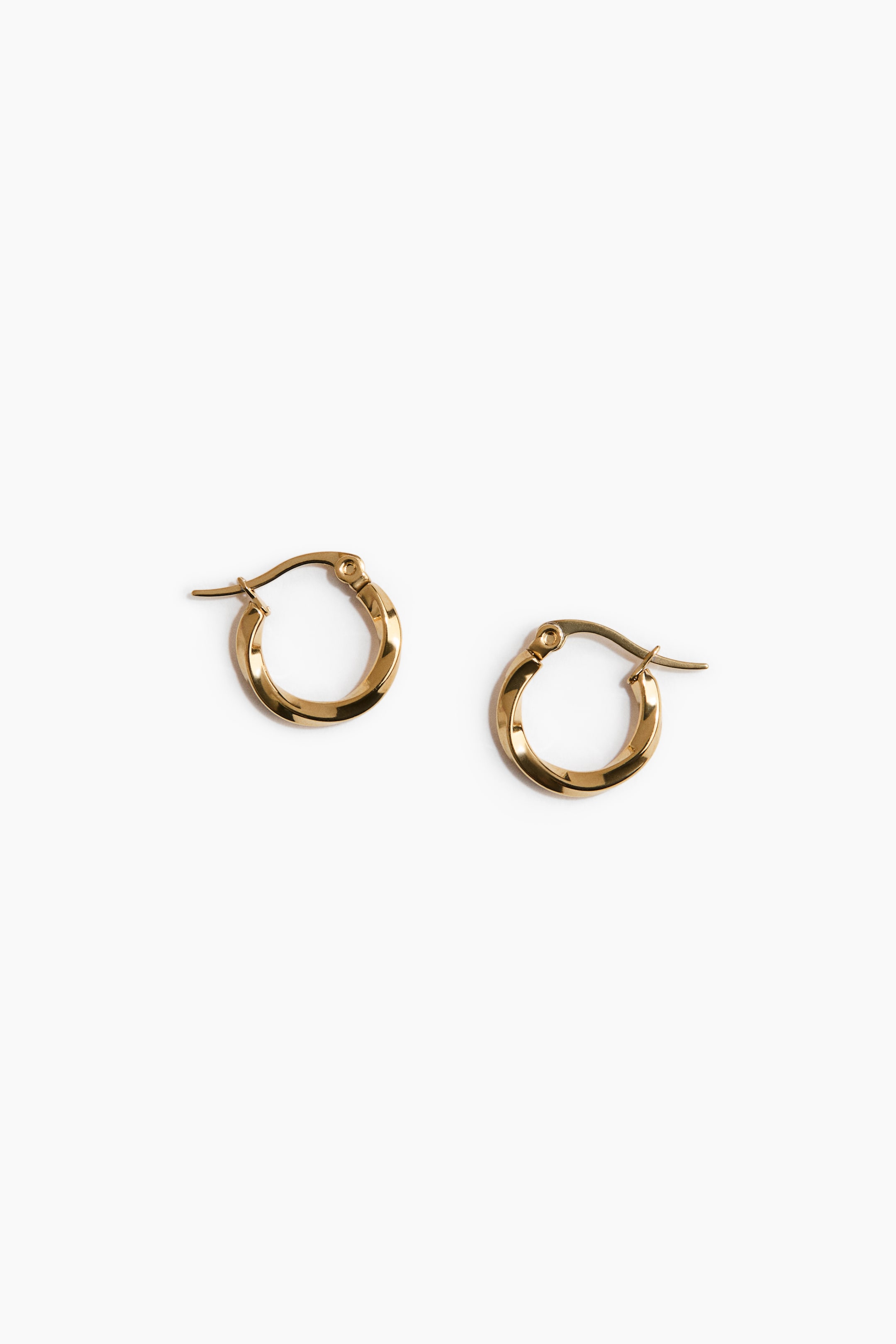 View larger image: Two gold-toned hoop earrings are on display, each featuring a twisted, faceted design. They present their front and inner surfaces, showcasing the hinged closure mechanism.