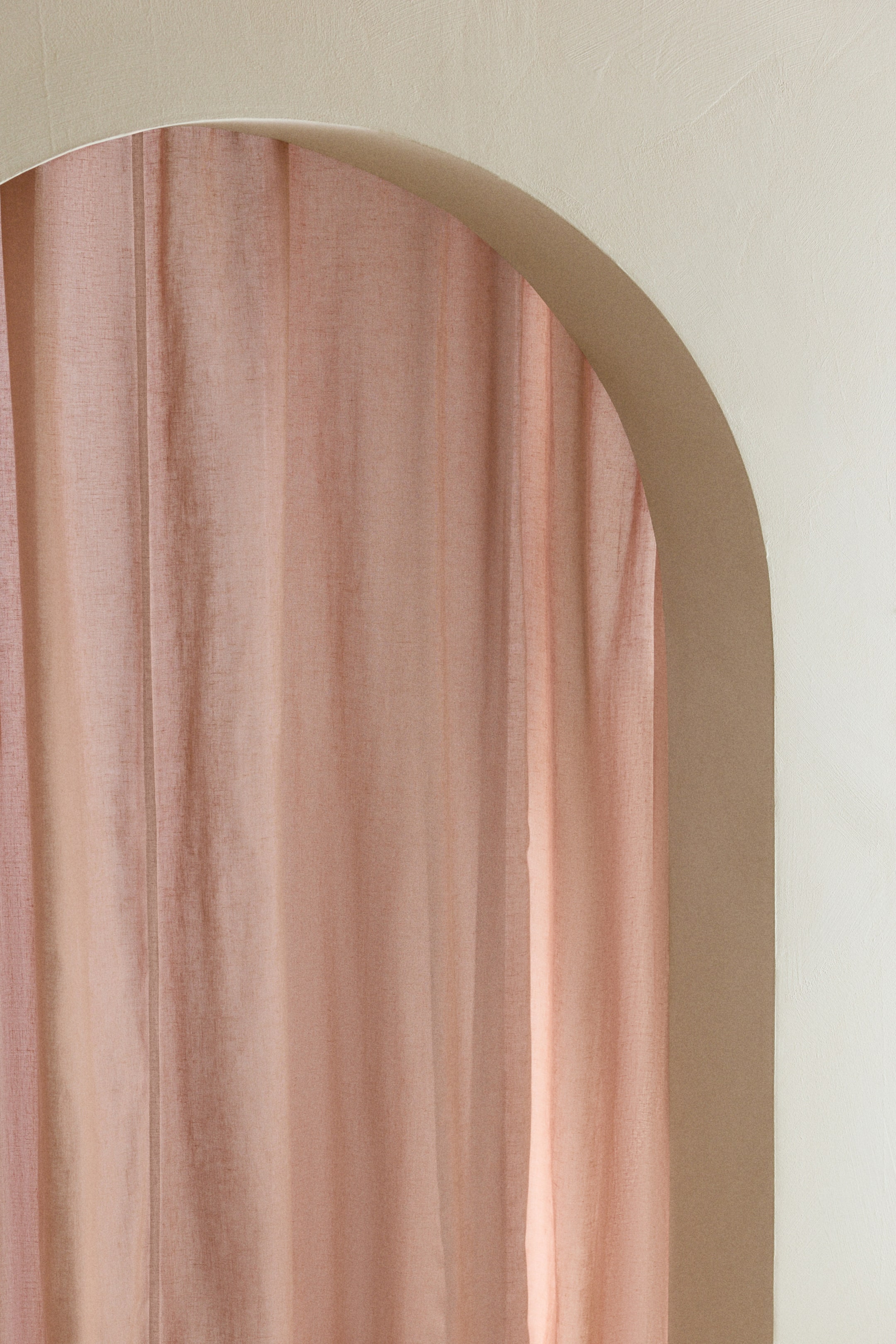 Größeres Bild anzeigen: Ein roséfarbener, transparenter Vorhang hängt vertikal und zeigt weiche Falten sowie eine dezente, strukturierte Webart.