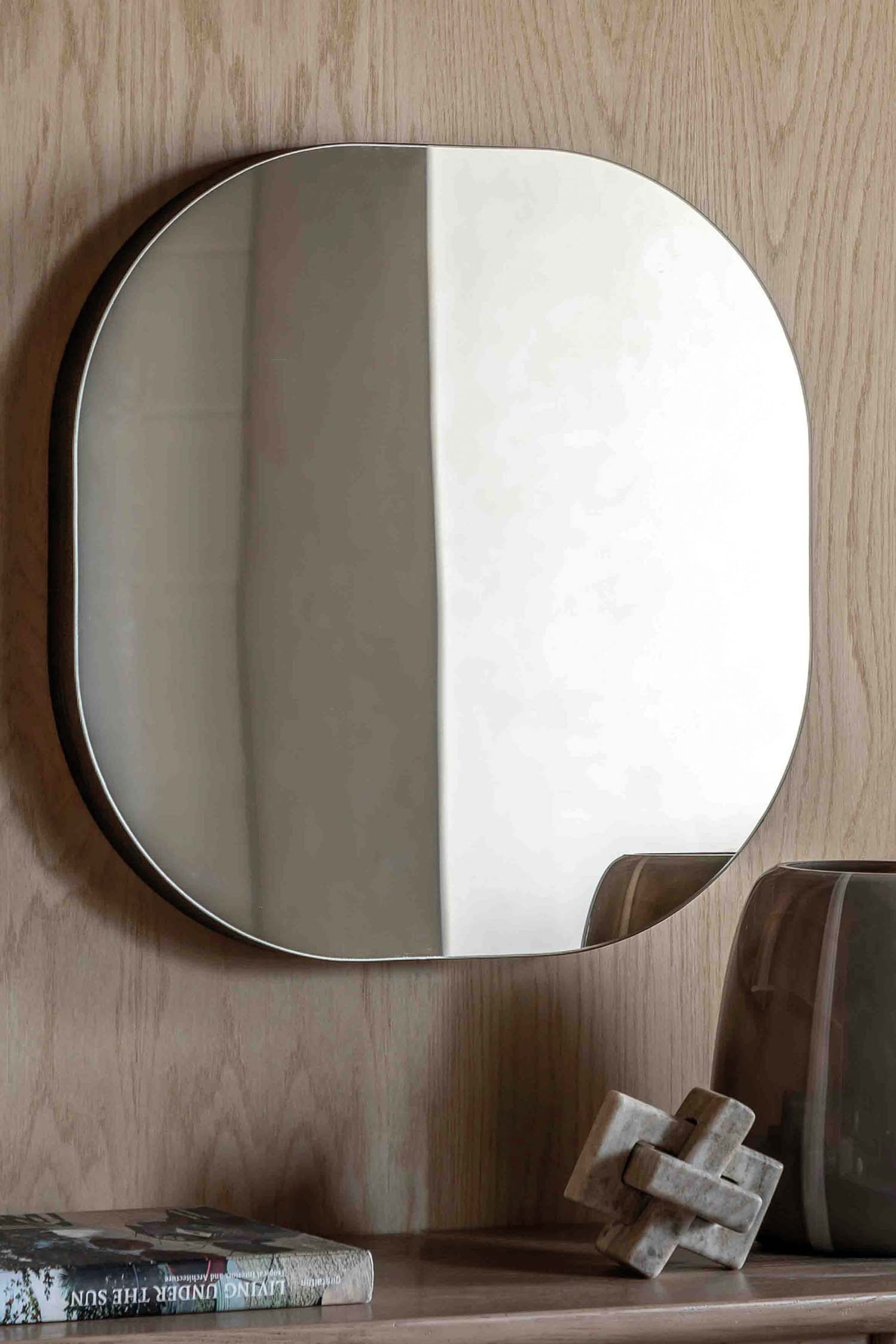 View larger image: A pill-shaped mirror features a slim, dark frame around its rounded corners, presenting its reflective surface directly forward.