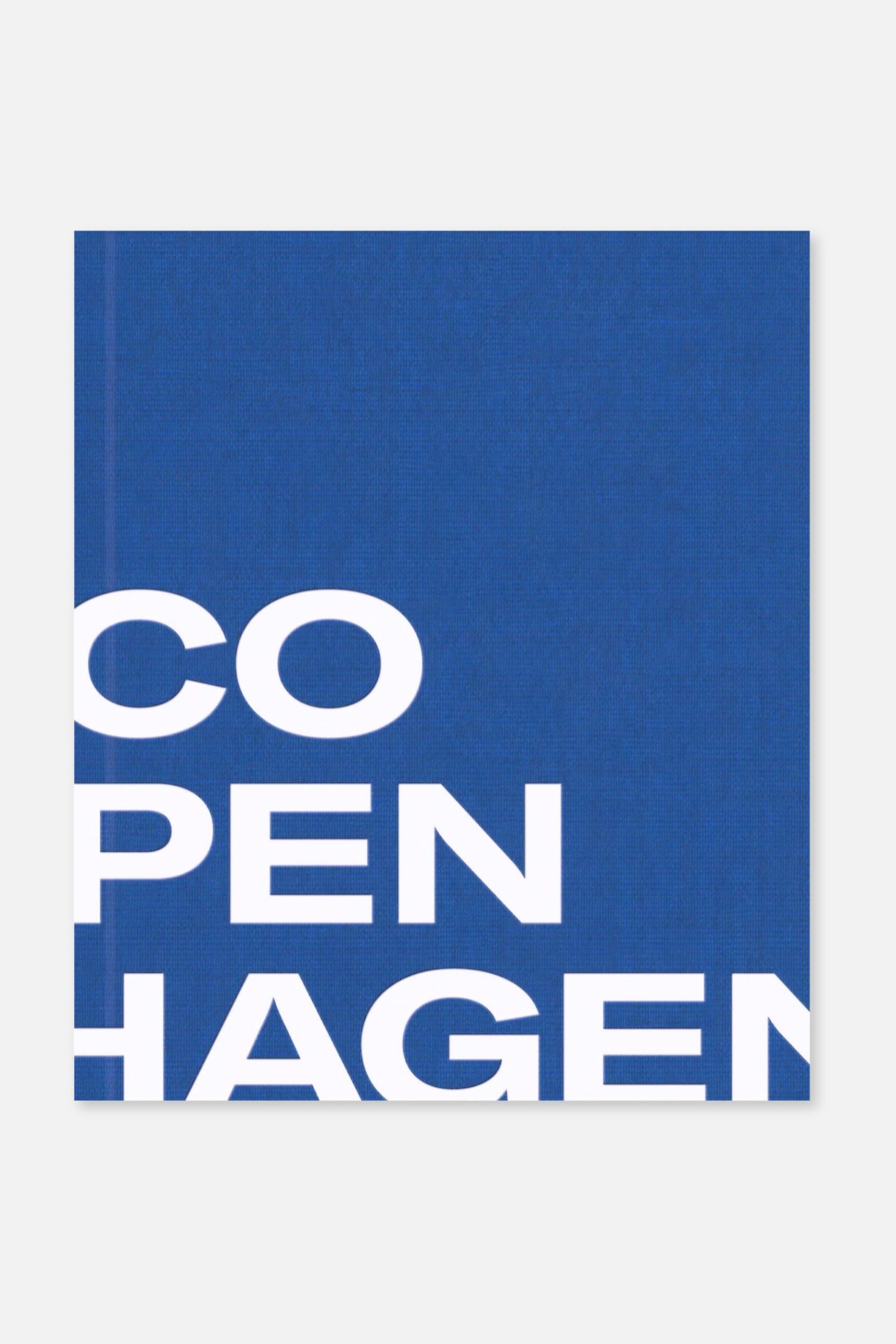 Ver imagen más grande: Un libro con una portada texturizada de color azul real muestra la palabra "COPENHAGEN" en una tipografía sans serif blanca, grande y en negrita, dispuesta verticalmente en tres líneas.