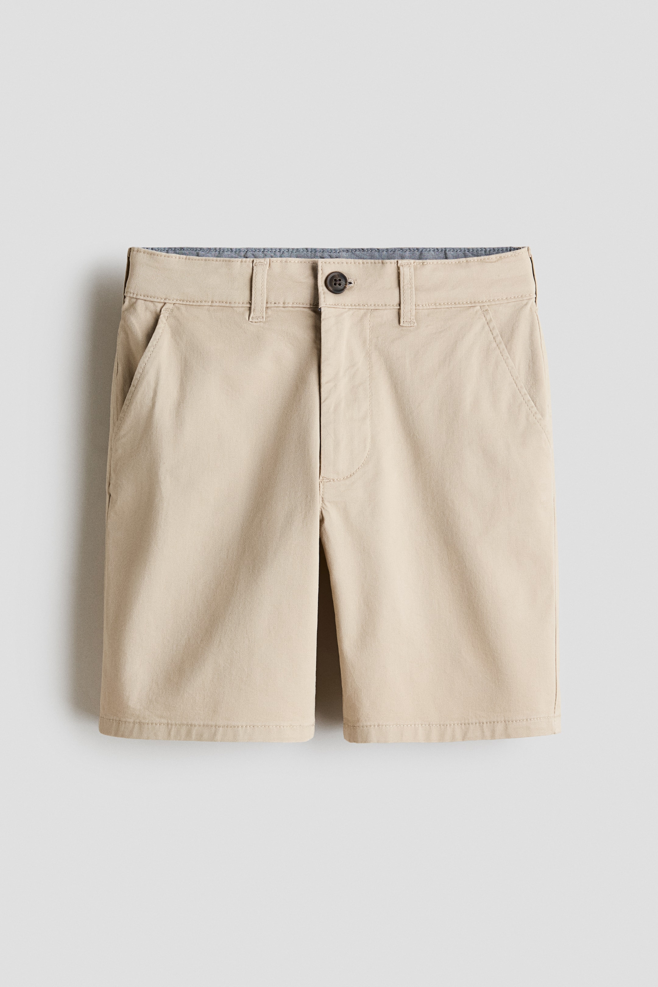 View larger image: A pair of light brown tailored shorts is shown front-facing, featuring a waistband with belt loops, a single button closure, and a visible zip fly. Diagonal side pockets are present on the front.
