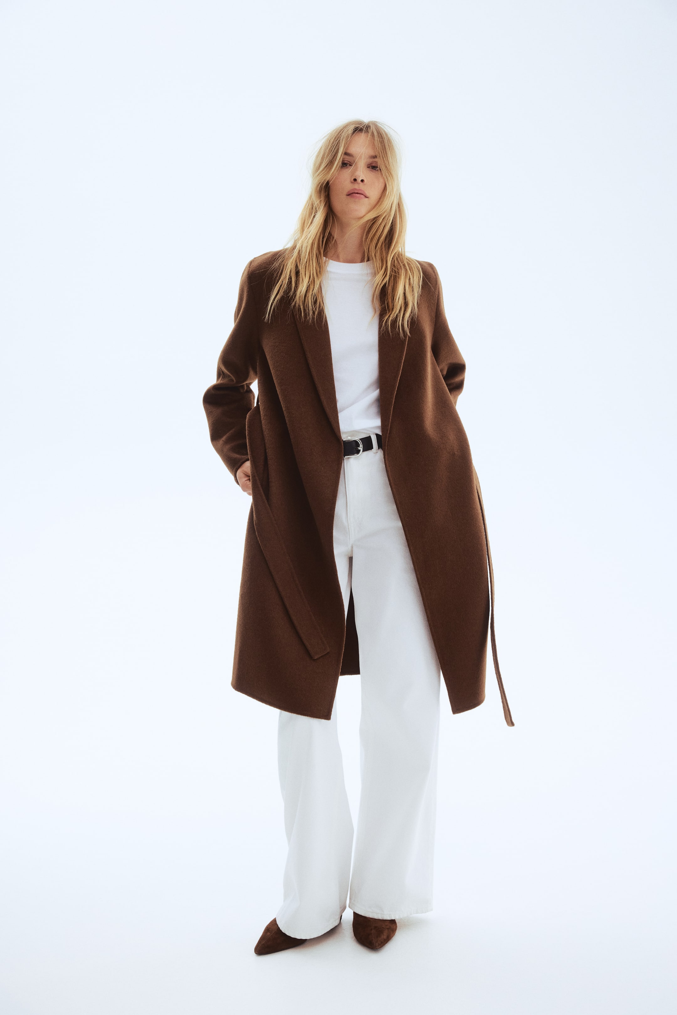 View larger image: A long brown coat featuring wide lapels and an open front, with its self-fabric belt hanging loose at the side.