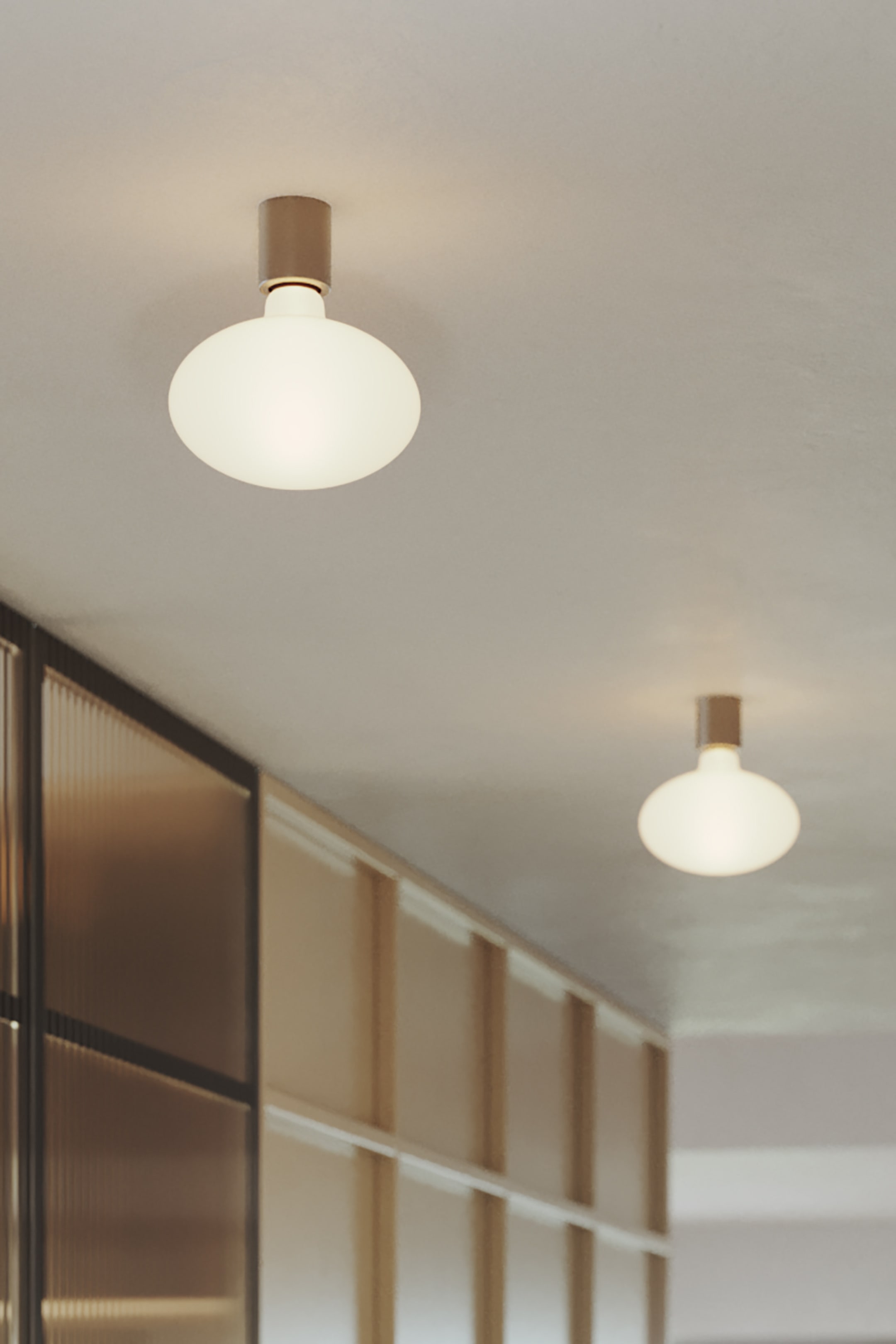 Grotere afbeelding bekijken: Een plafondlamp met een cilindrische metalen basis die aan het plafond is bevestigd, met een verlichte, ondoorzichtige witte globe diffuser die naar beneden hangt.