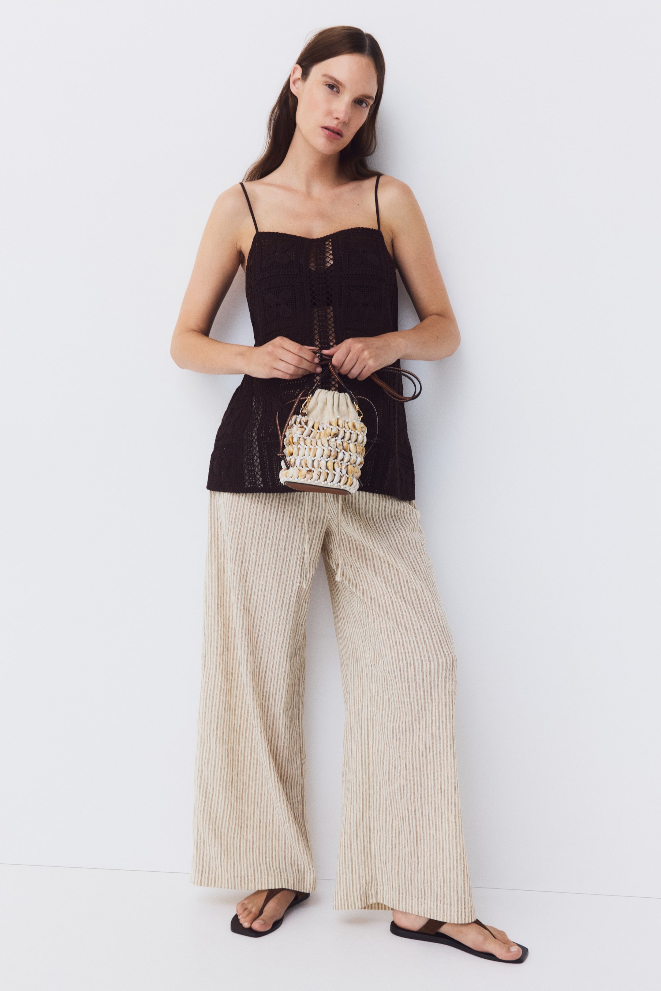 Ver imagen más grande: Pantalones de corte holgado en jersey texturizado a rayas de color beige claro llevados por la modelo, con cintura baja, un cordón estrecho y perneras anchas.