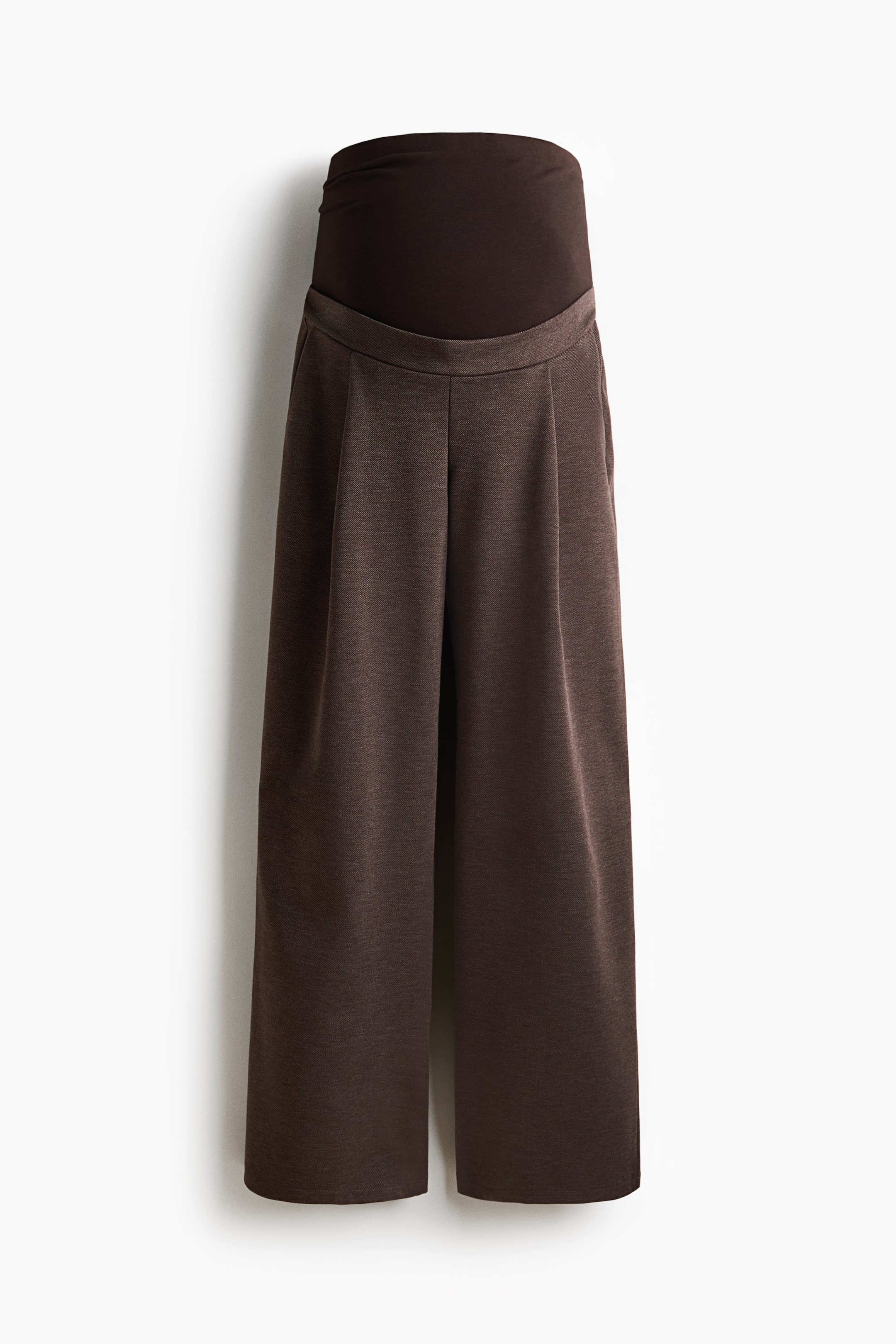 View larger image: Dark brown maternity wide-leg pants are shown from the front, featuring a smooth, dark-brown over-the-belly panel. The pants display a heathered brown textured fabric with pleats running down the front of each leg and visible side pockets.
