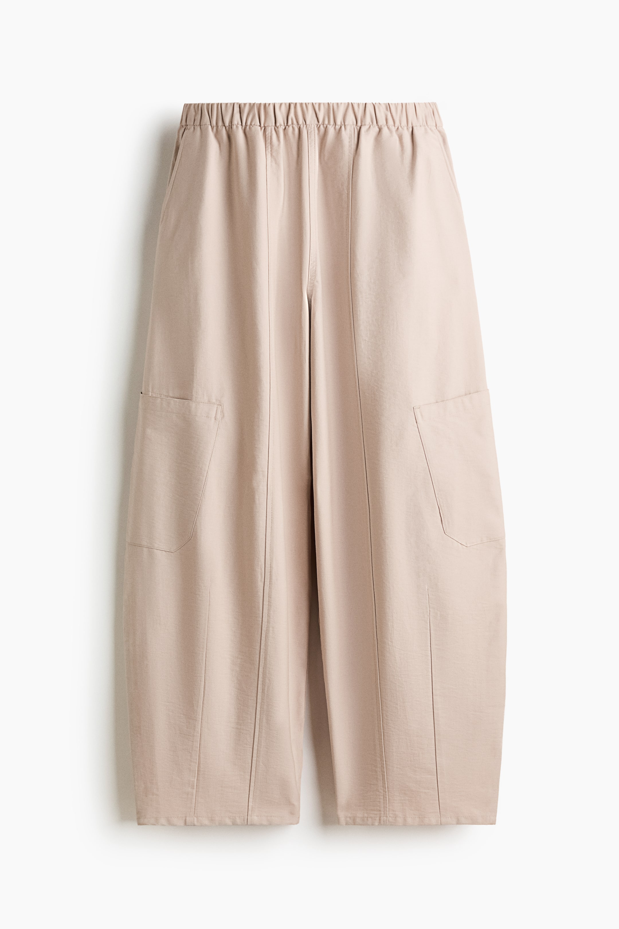 拡大画像を表示: ライトベージュのパンツが前面から見え、ウエスト部分にはゴムが入り、ワイドでクロップドされたレッグが特徴です。前面には大きなパッチポケットが2つあり、各脚に1つずつ配置されています。各脚の中央には縦の縫い目が走っています。