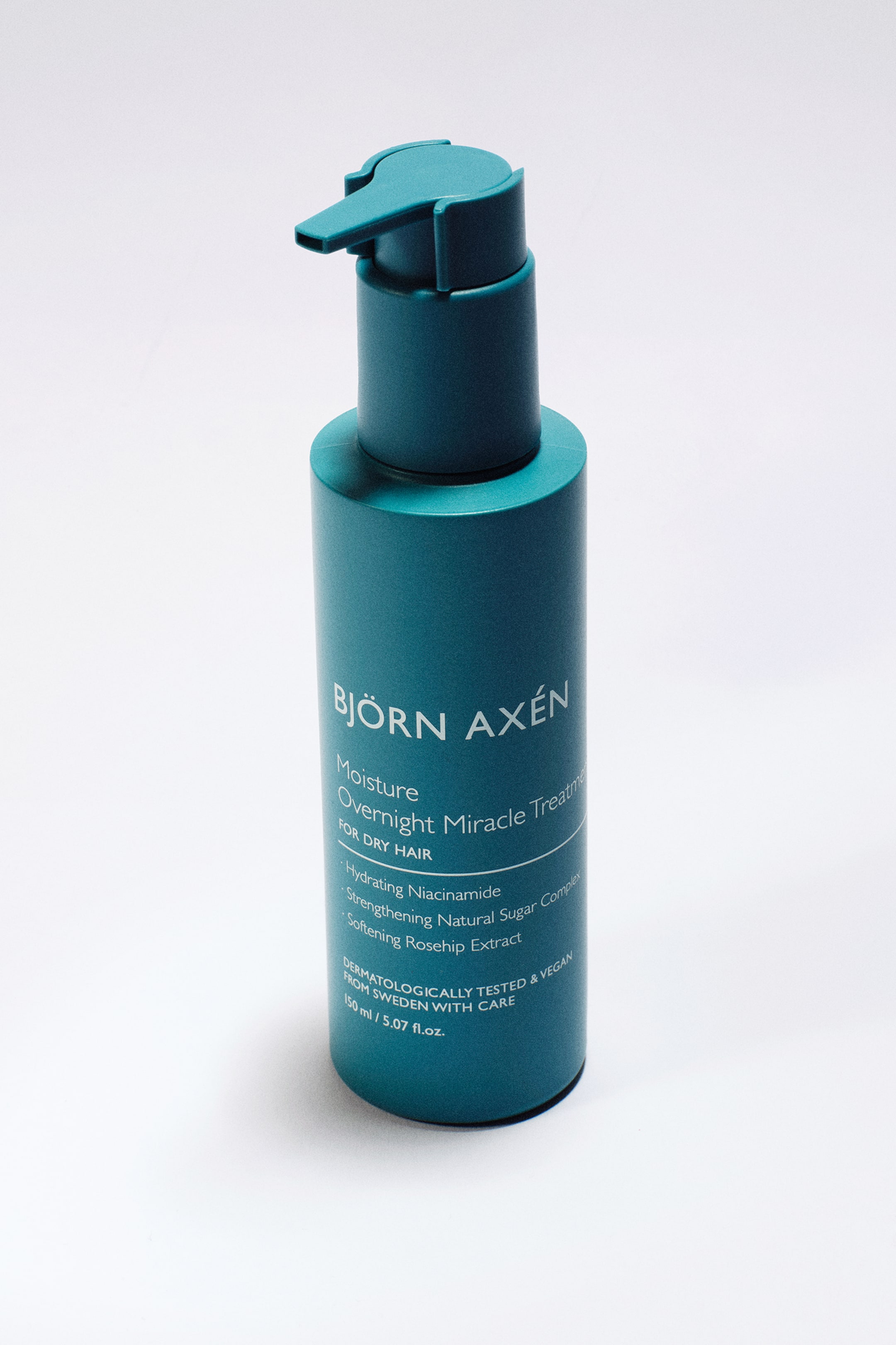 Visa större bild: Björn Axén Moisture Overnight Miracle Treatment presenteras som en cylindrisk, mörk teal flaska, något vinklad åt höger och framåt. Den har en matchande pumpdispenser på toppen, och etiketten visar produktnamnet och ingrediensdetaljer.
