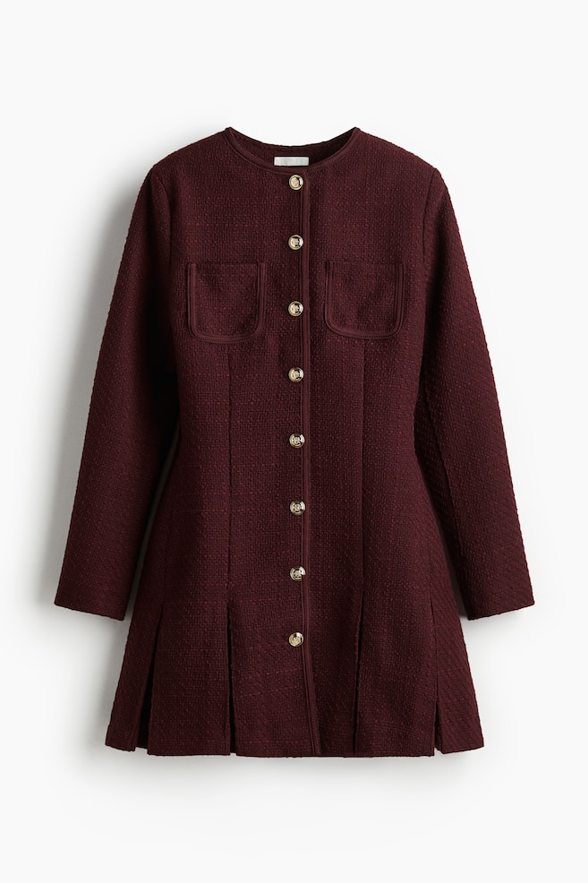 Un abito in tweed bordeaux è presentato dalla parte anteriore, caratterizzato da uno scollo rotondo, maniche lunghe e una chiusura frontale completa con bottoni dorati in rilievo. Include due tasche applicate arrotondate sul petto e la parte inferiore dell'abito è stilizzata con pieghe. - 1