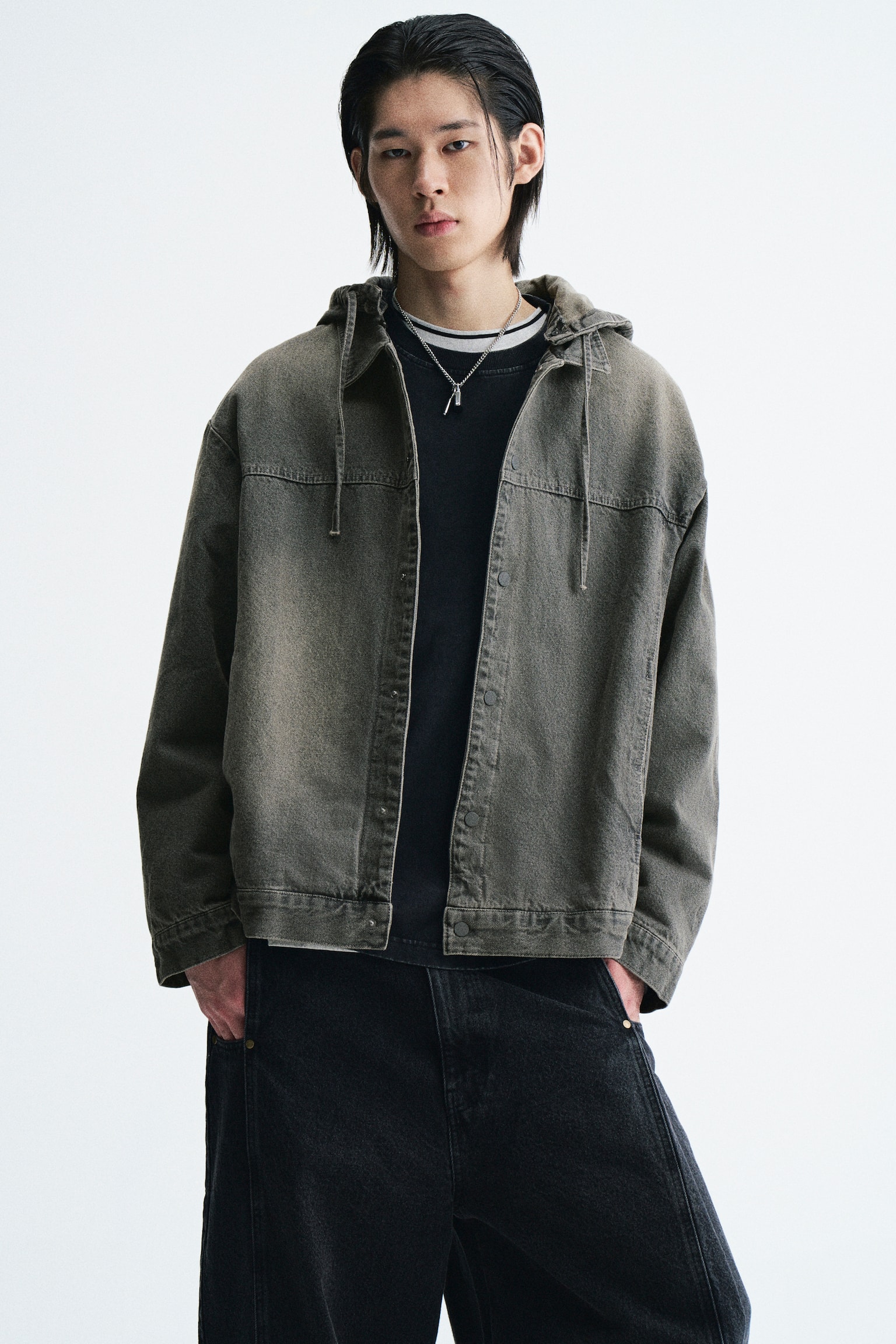 Má»t chiáº¿c Ã¡o khoÃ¡c denim mÃ u nÃ¢u xÃ¡m báº¡c mÃ u vá»i cá» Ã¡o, mÅ© trÃ¹m cÃ³ dÃ¢y rÃºt, vai rÆ¡i vÃ  pháº§n trÆ°á»c cÃ i nÃºt báº¥m Äang ÄÆ°á»£c ngÆ°á»i máº«u máº·c má». Ão khoÃ¡c ÄÆ°á»£c phá»i bÃªn ngoÃ i Ã¡o thun cá» trÃ²n mÃ u Äen vÃ  káº¿t há»£p vá»i quáº§n jeans tá»i mÃ u, dÃ¡ng rá»ng. - 1