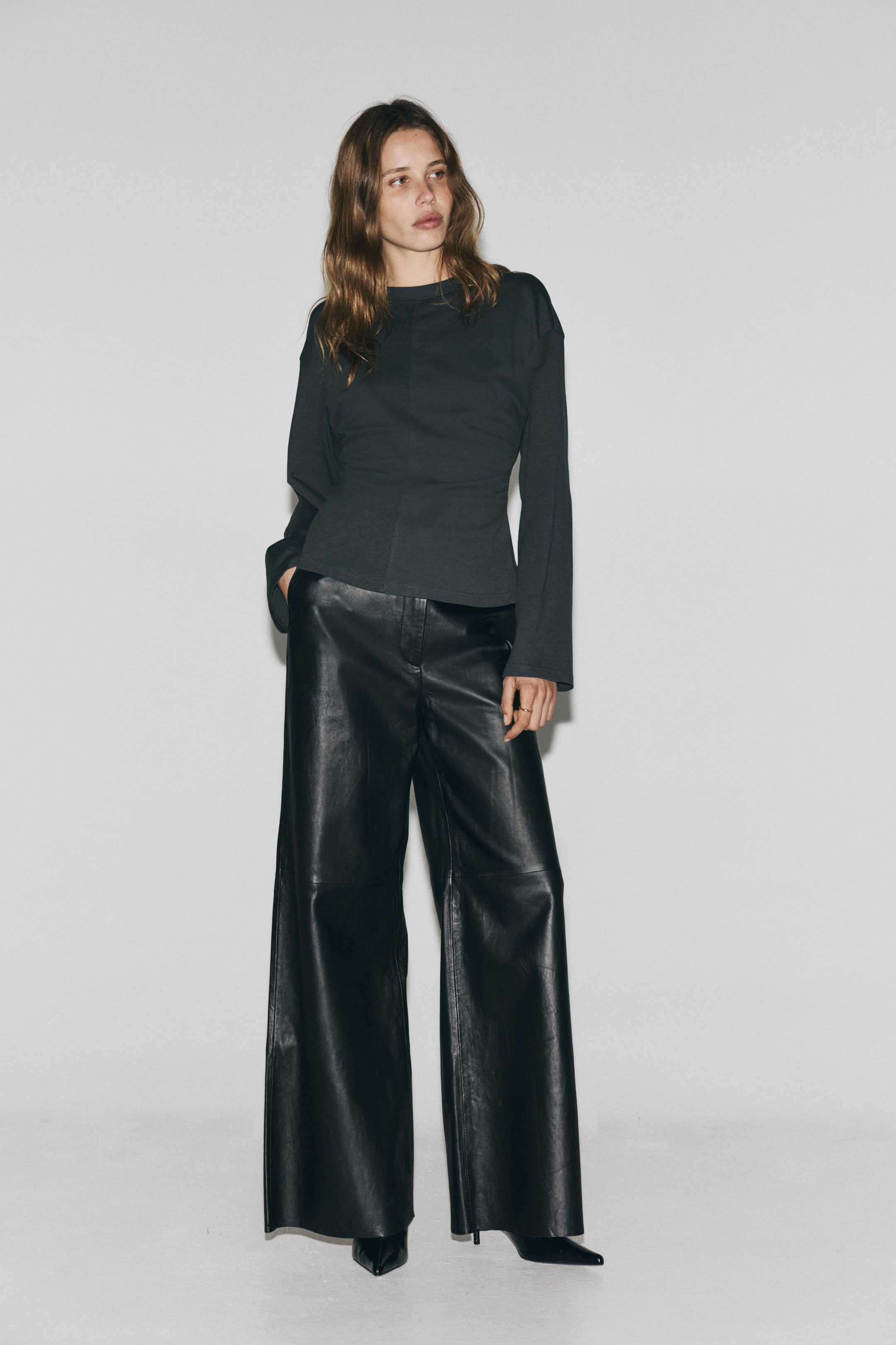 Преглед на по-голямо изображение: Тъмно сиво трико от памук с кръгло деколте, спуснати рамене и дълги ръкави. То е проектирано с набори отстрани, които създават вталена талия и разкроен подгъв.