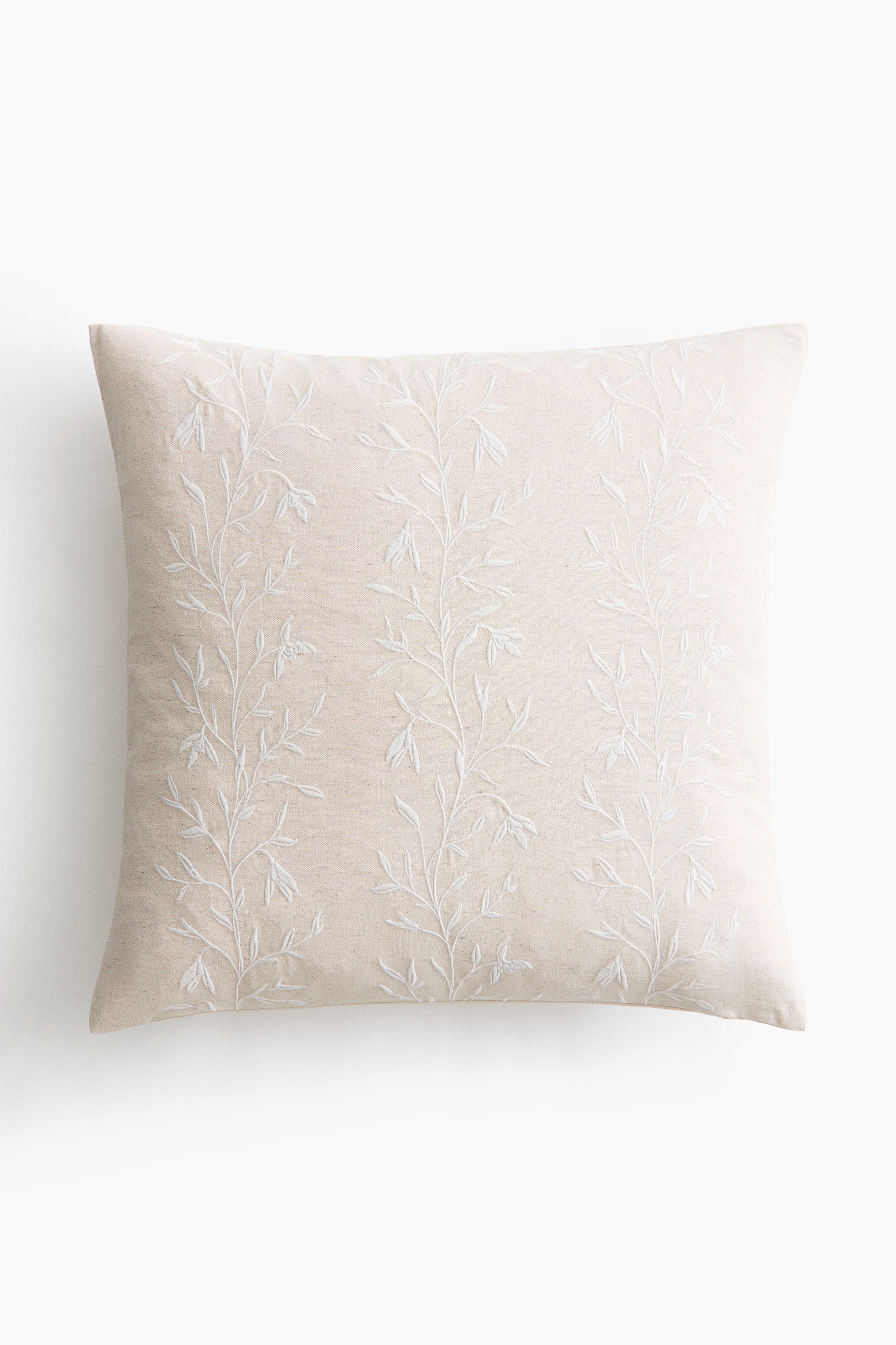 View larger image: A square throw cushion in a light beige fabric is facing the front, featuring three vertical columns of delicate white embroidered vines with leaves and small blossoms.