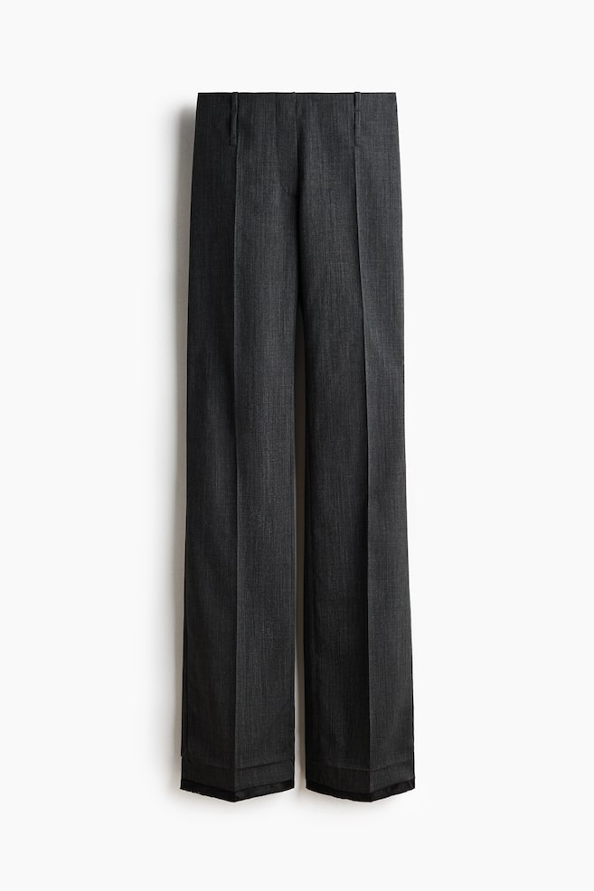 Dark gray trousers in a subtle woven fabric are hanging vertically, facing forward. They are featuring a flat waistband with belt loops, prominent front creases running down the straight-cut legs, and a dark, clean-finished edge at the bottom hem. - 1
