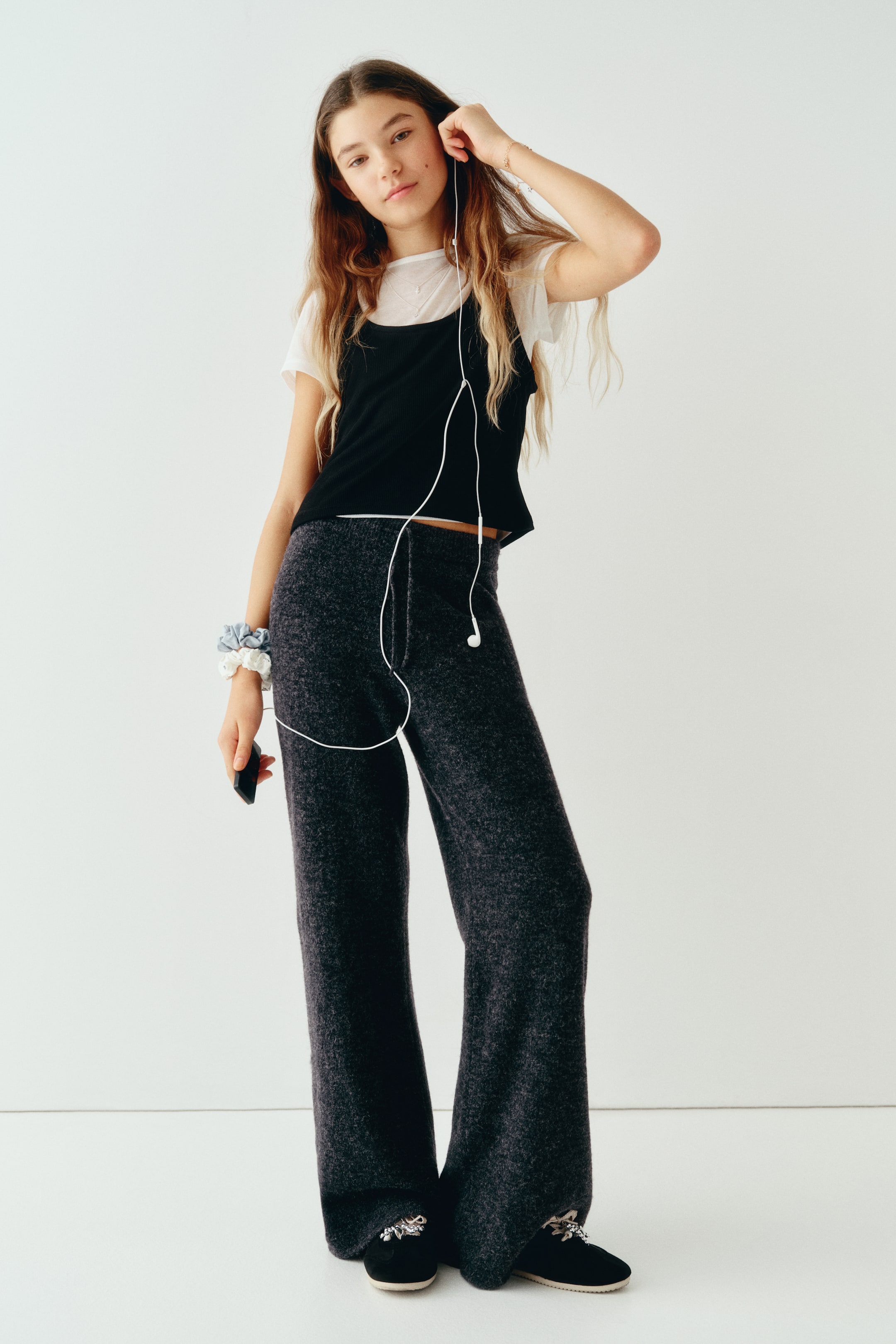 View larger image: Fine-knit joggers in dark grey marl are shown from the front, featuring a relaxed wide-leg silhouette and an elasticated waistband with a matching drawstring. The soft-textured joggers fall loosely to the feet, showcasing their comfortable, draped fit.