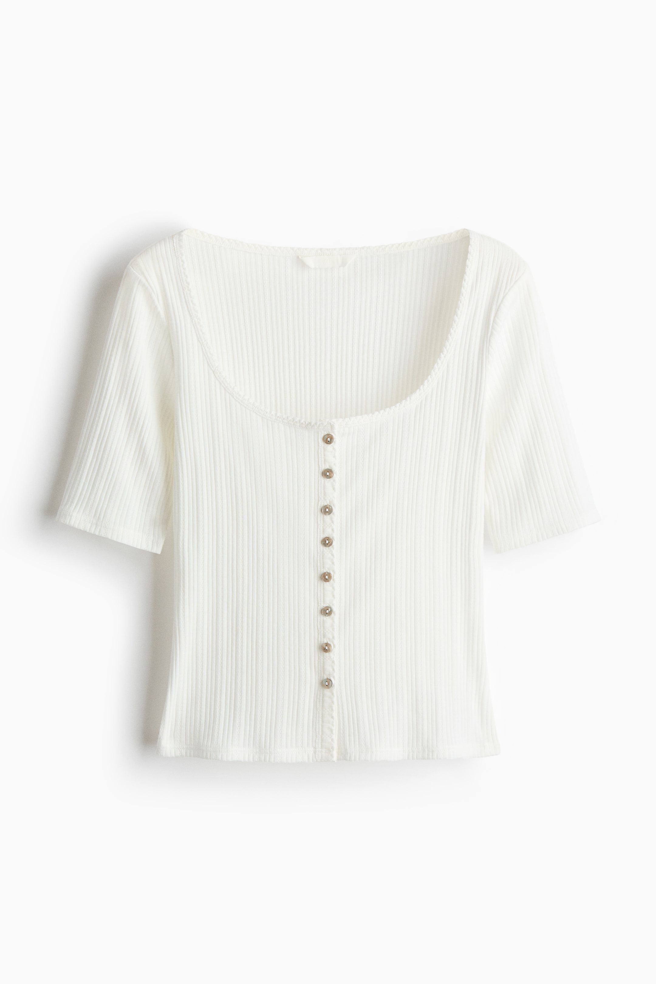 Se større billede: En tætsiddende, kortærmet top præsenteres foran, fremstillet af en blød pointelle-strik og med en rund halsudskæring, knapper ned foran og diskret bølgede kanter langs halsudskæringen og knapbåndet.