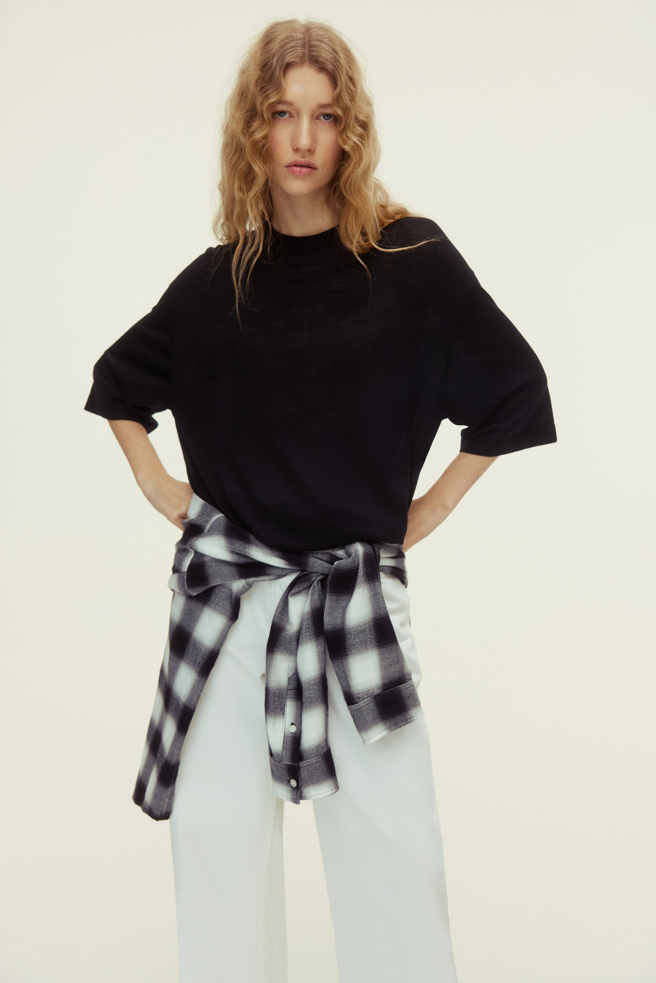 Voir une image plus grande: Un t-shirt noir présente un col rond haut et des manches courtes et amples. Il offre une coupe décontractée, légèrement oversize.