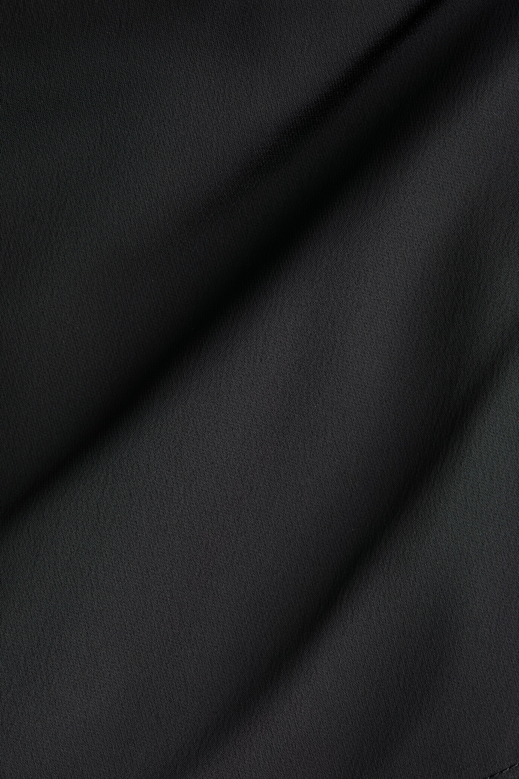 Agrandir l'image: Le tissu noir présente des plis doux, mettant en valeur sa surface subtilement texturée et fine.