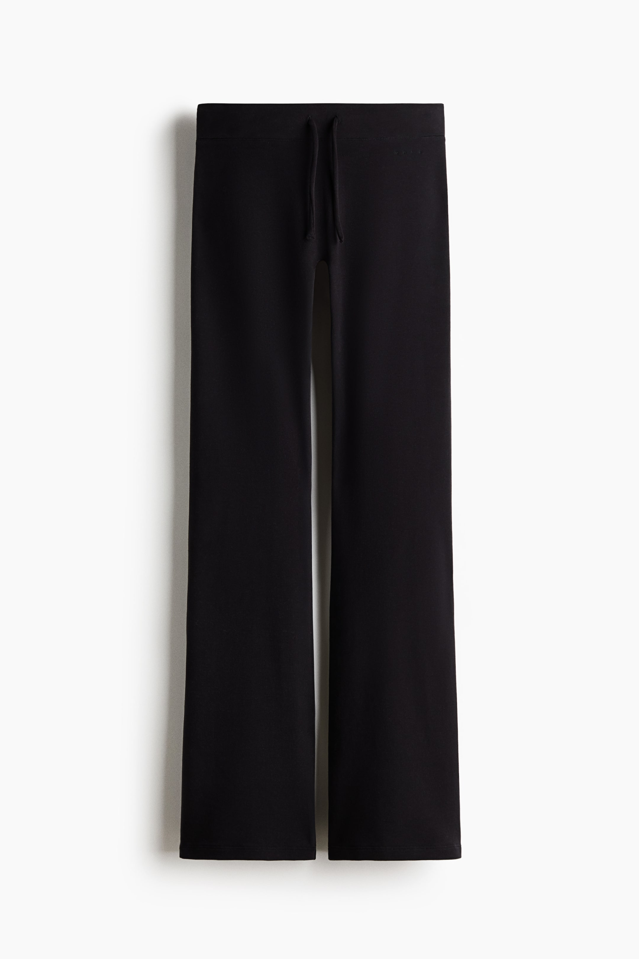 View larger image: A pair of black wide-leg trousers is hanging in a front view, featuring a flat waistband with matching drawstrings and displaying a relaxed, slightly flared silhouette.