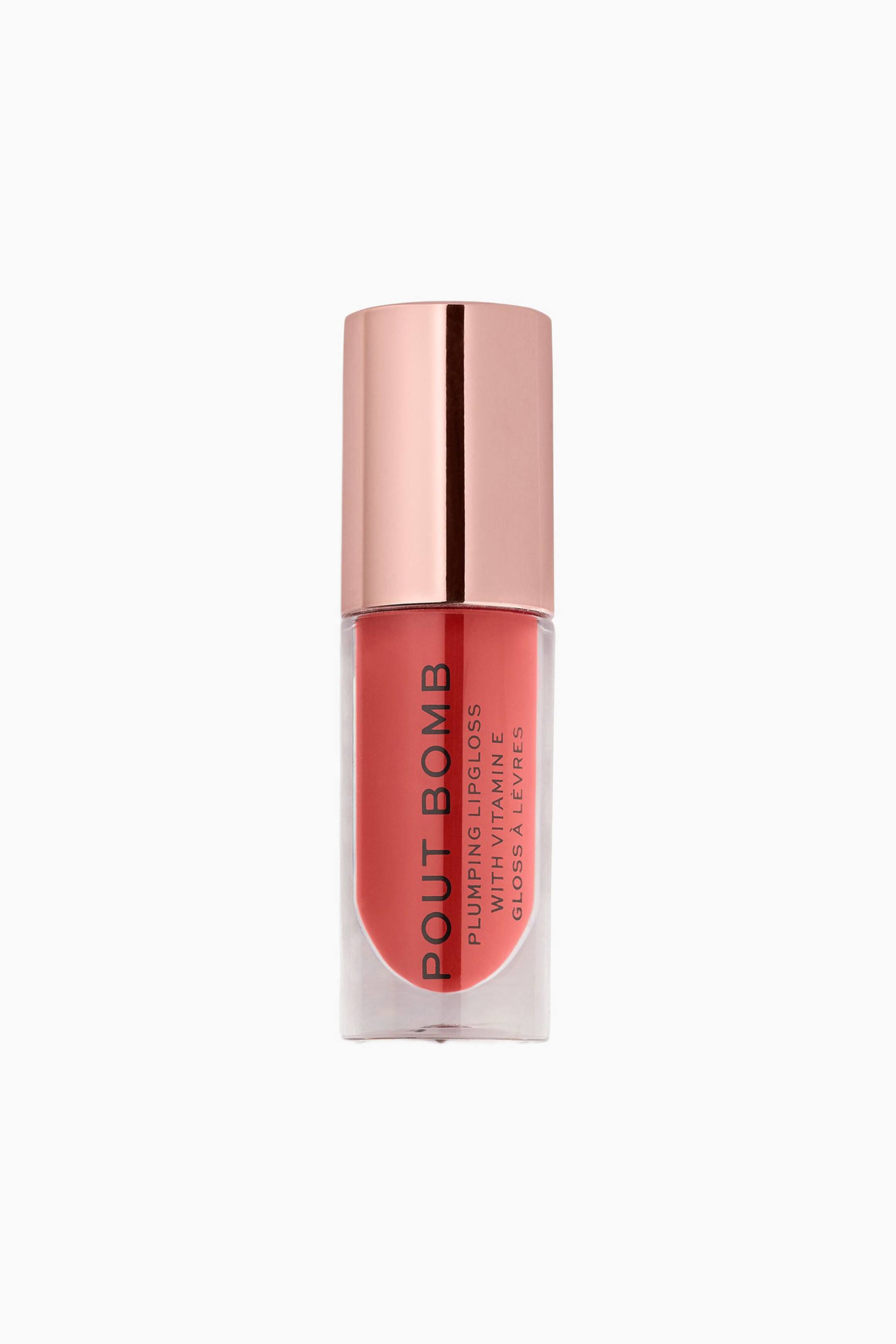 Größeres Bild ansehen: Ein aufrecht stehender Lipgloss in Tubenform ist in frontaler Ansicht zu sehen und verfügt über einen transparenten zylindrischen Behälter, der einen korallenrosa Farbton zeigt. Auf der Flasche ist vertikal schwarzer Text mit der Aufschrift „POUT BOMB“ zu sehen, und ein reflektierender, metallischer, roségoldener zylindrischer Deckel verschließt die Oberseite.