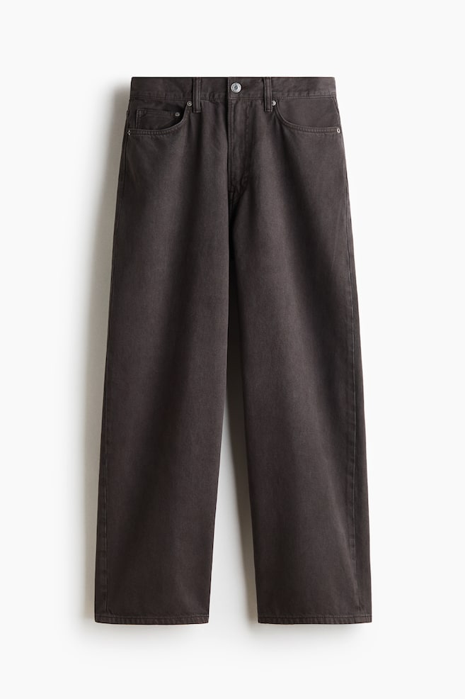 A pair of dark brown 5-pocket denim jeans is shown from the front, featuring a regular waist, a button-and-zip fly, and a dropped crotch. The jeans are displaying a baggy, wide-leg silhouette with rounded legs. - 1