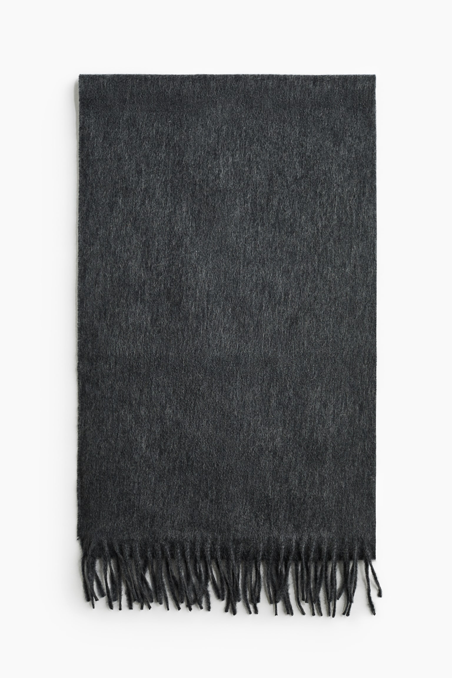 Una sciarpa in cashmere grigio scuro è posizionata frontalmente, distesa in piano per mostrare la sua morbida texture spazzolata. La sciarpa presenta dettagli con frange intrecciate lungo il bordo inferiore visibile.