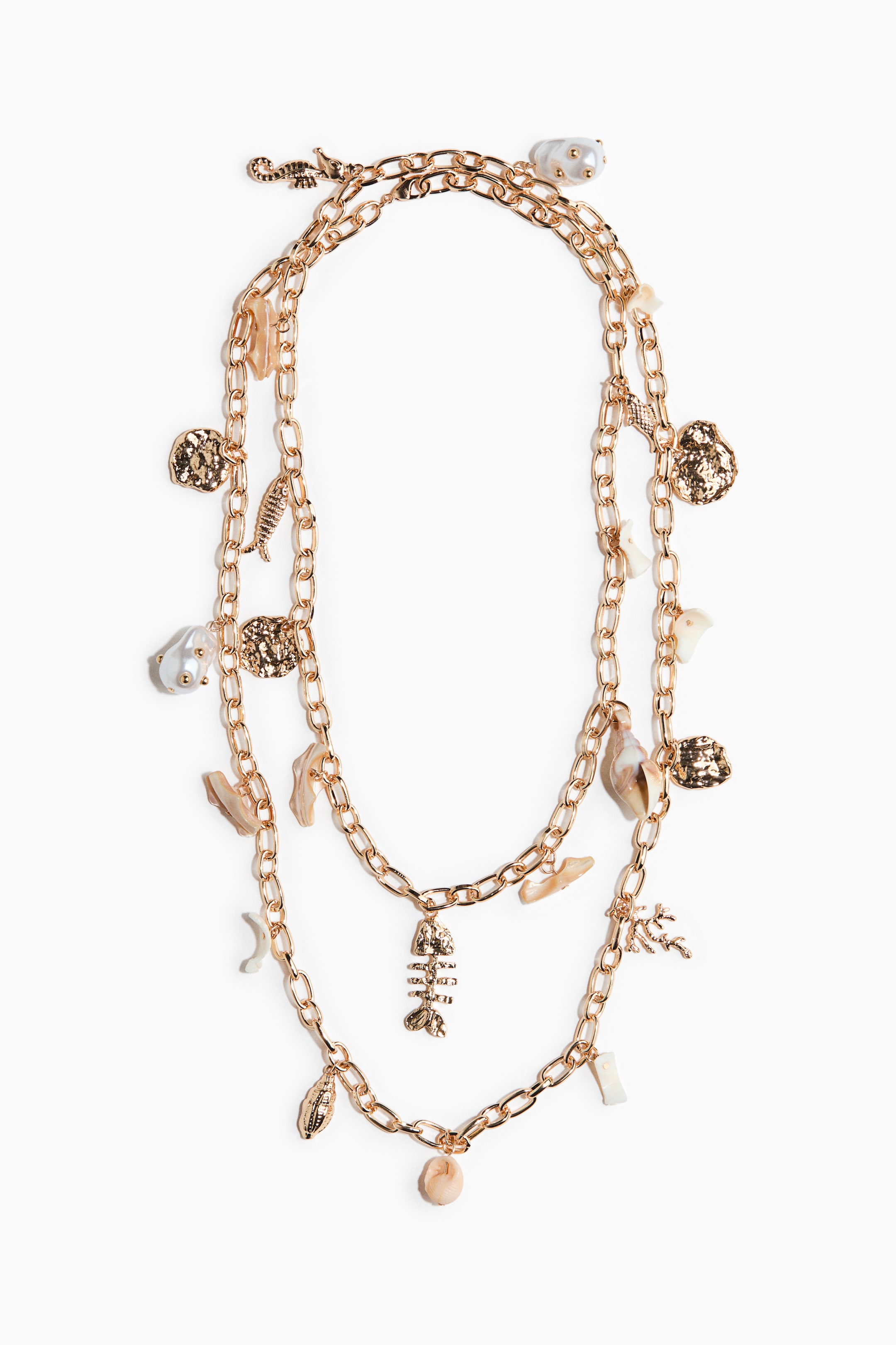 View larger image: "A gold-toned layered necklace showcasing two chains. Various charms dangle from the chains, including gold-toned textured shapes, a fish skeleton, a seahorse, coral, and natural elements like shells, irregular pearls, and small stones."