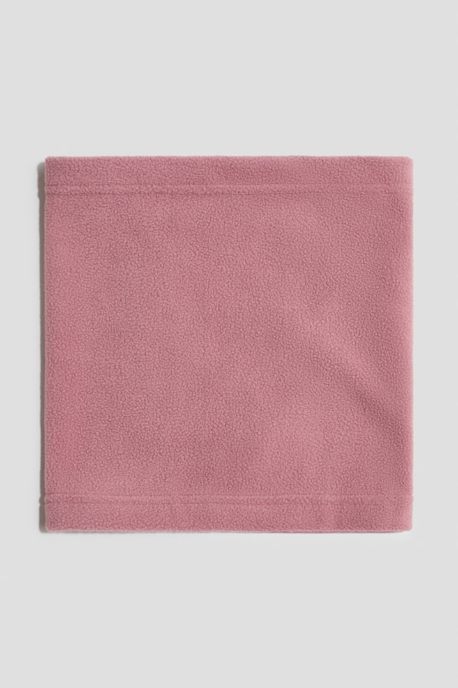 Una bufanda tubular de tela polar rosa empolvado está colocada plana, mostrando su forma rectangular desde el frente. Presenta dobladillos cosidos en los bordes superior e inferior, resaltando el material polar suave y texturizado. - 1