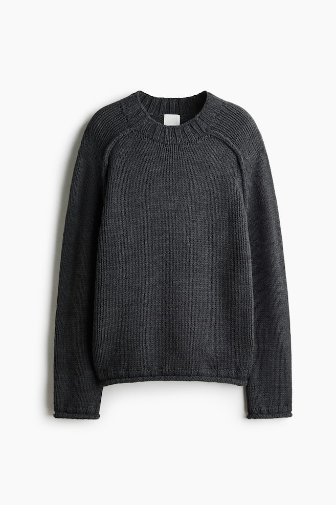 A dark grey knit sweater is showing in a front-facing view, featuring a ribbed crewneck, raglan sleeves, and ribbed details at the cuffs and hem. - 1