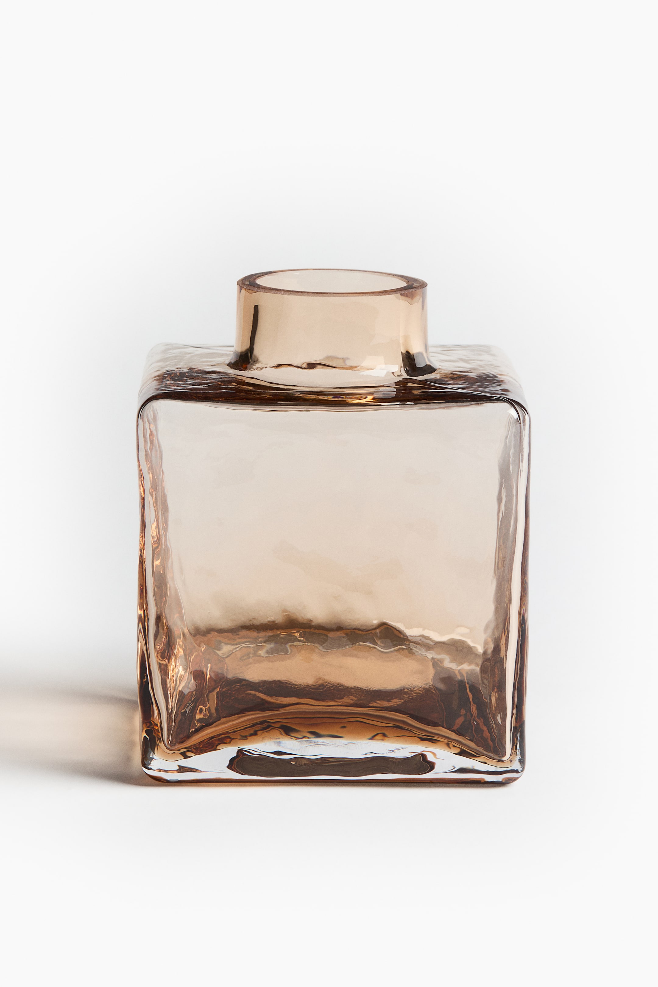 View larger image: A square amber glass vase is displaying its front, featuring a textured, rippled surface. A narrow, cylindrical opening is rising from the center of its top.