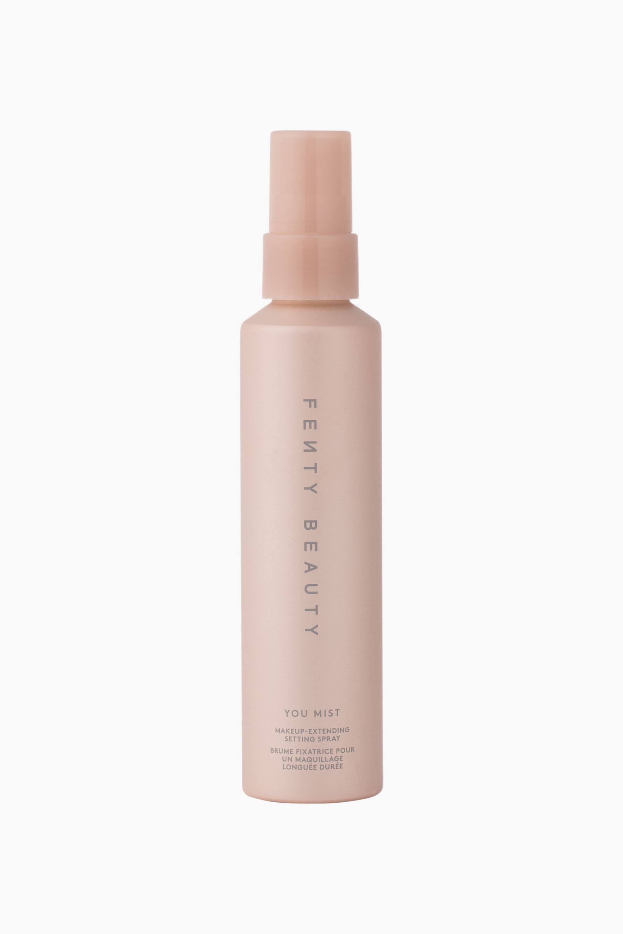 Näytä suurempi kuva: Fenty Beauty You Mist Makeup-extending Setting Spray on pystyasennossa eteenpäin suuntautuvassa kuvassa, esitellen sen siroa, mattapintaista persikanvaaleanpunaista sylinterimäistä pulloa ja siihen sopivaa korkkia. Tuotemerkin nimi "FENTY BEAUTY" kulkee pystysuunnassa keskellä hillityn harmaalla fontilla, ja tuotetiedot näkyvät lähellä alaosaa.