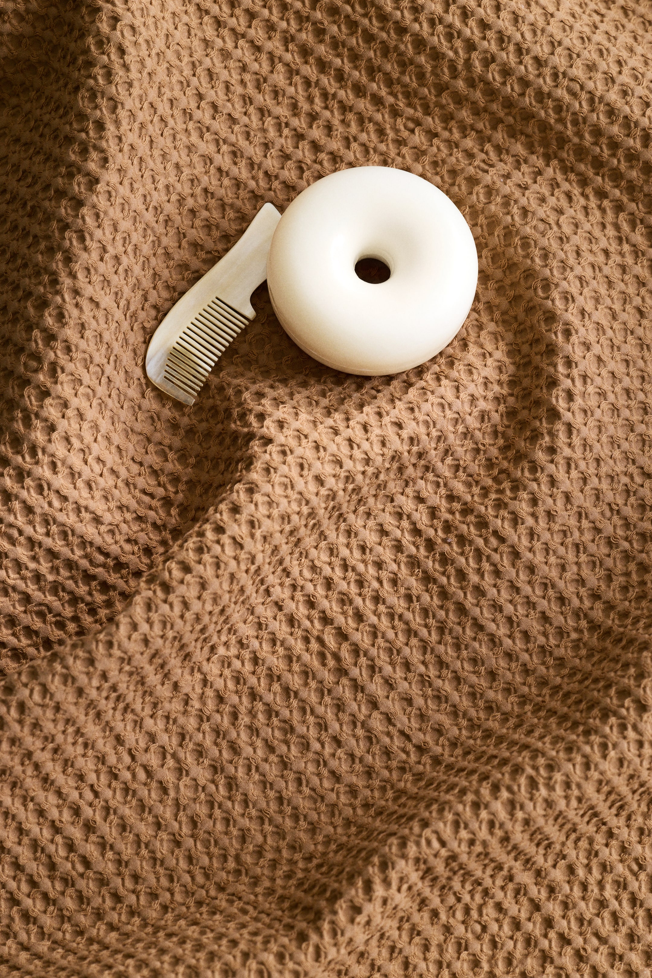 이미지 확대 보기: 갈색 손수건은 부드러운 와플 직조의 면 소재 질감을 보여줍니다. 수건은 드레이프되어 표면에 부드러운 주름과 그림자를 형성합니다.