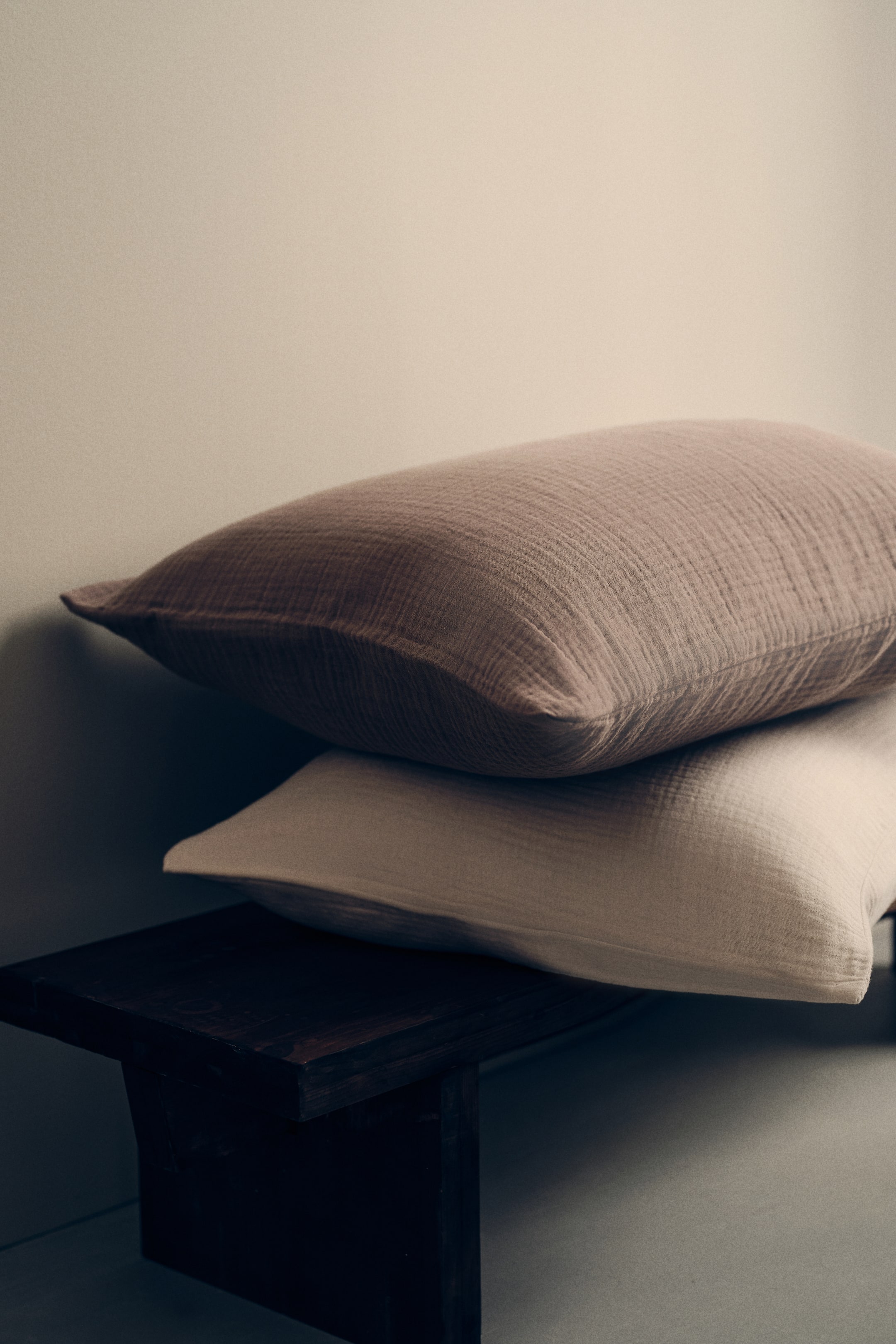 Vezi imaginea mai mare: Două perne dreptunghiulare sunt așezate una peste alta, prezentând o textură de muselină încrețită. Perna de sus este de un mov pal, iar perna de jos este de un bej deschis.
