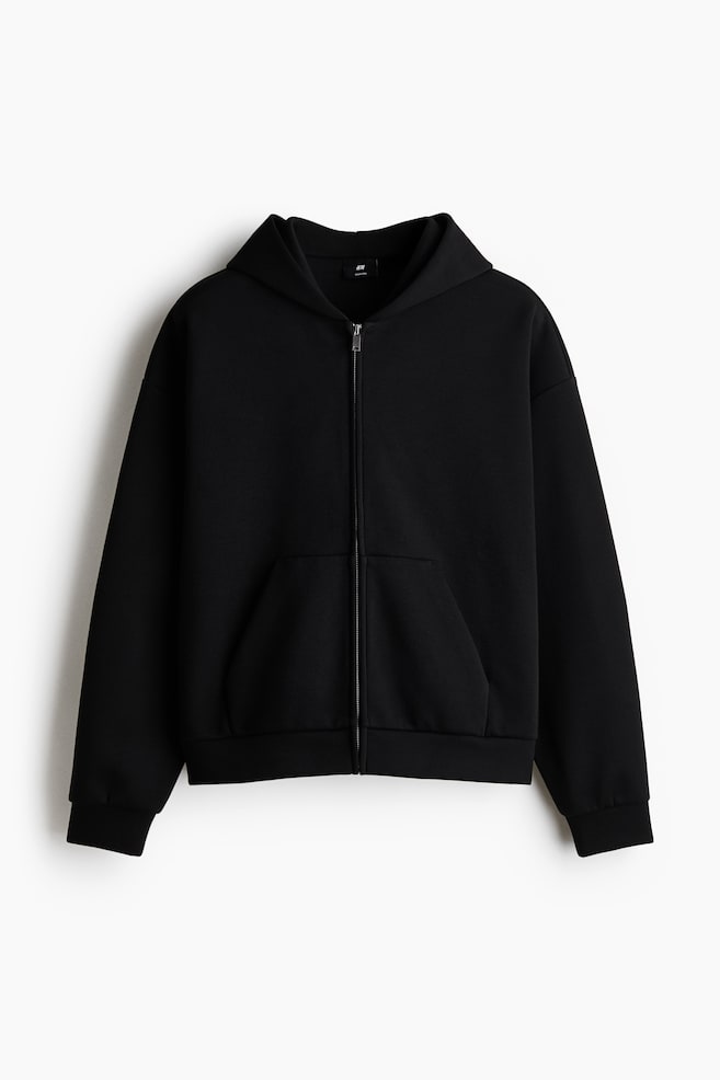 A black full-zip hoodie is presenting its front, featuring a draped hood, a silver-toned central zipper, and a large kangaroo pocket. - 1