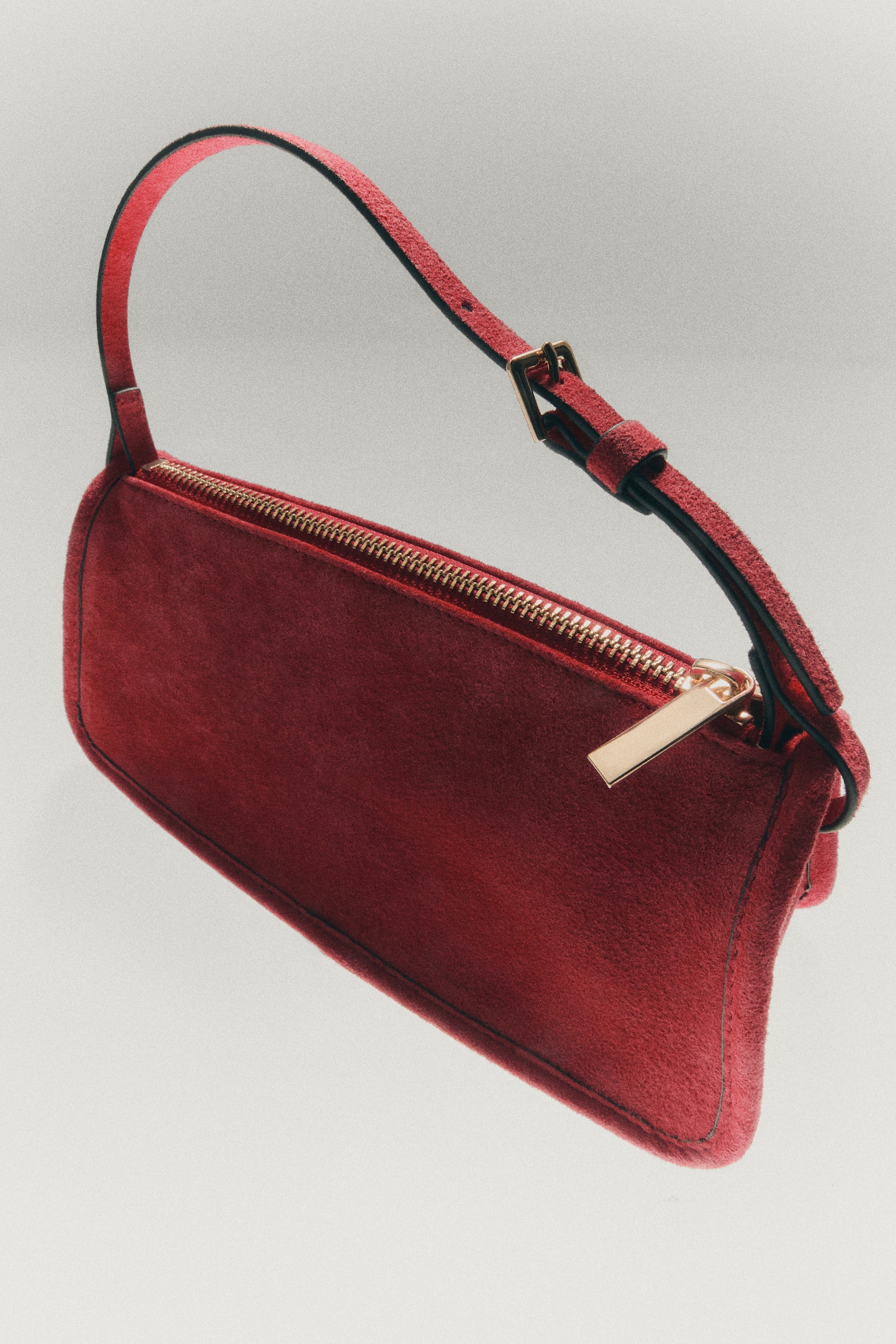 A red calf hair handbag is facing front, showcasing a rectangular body with a gold-tone top zip. It features a slender black handle with red edging and a gold-tone buckle. - 1