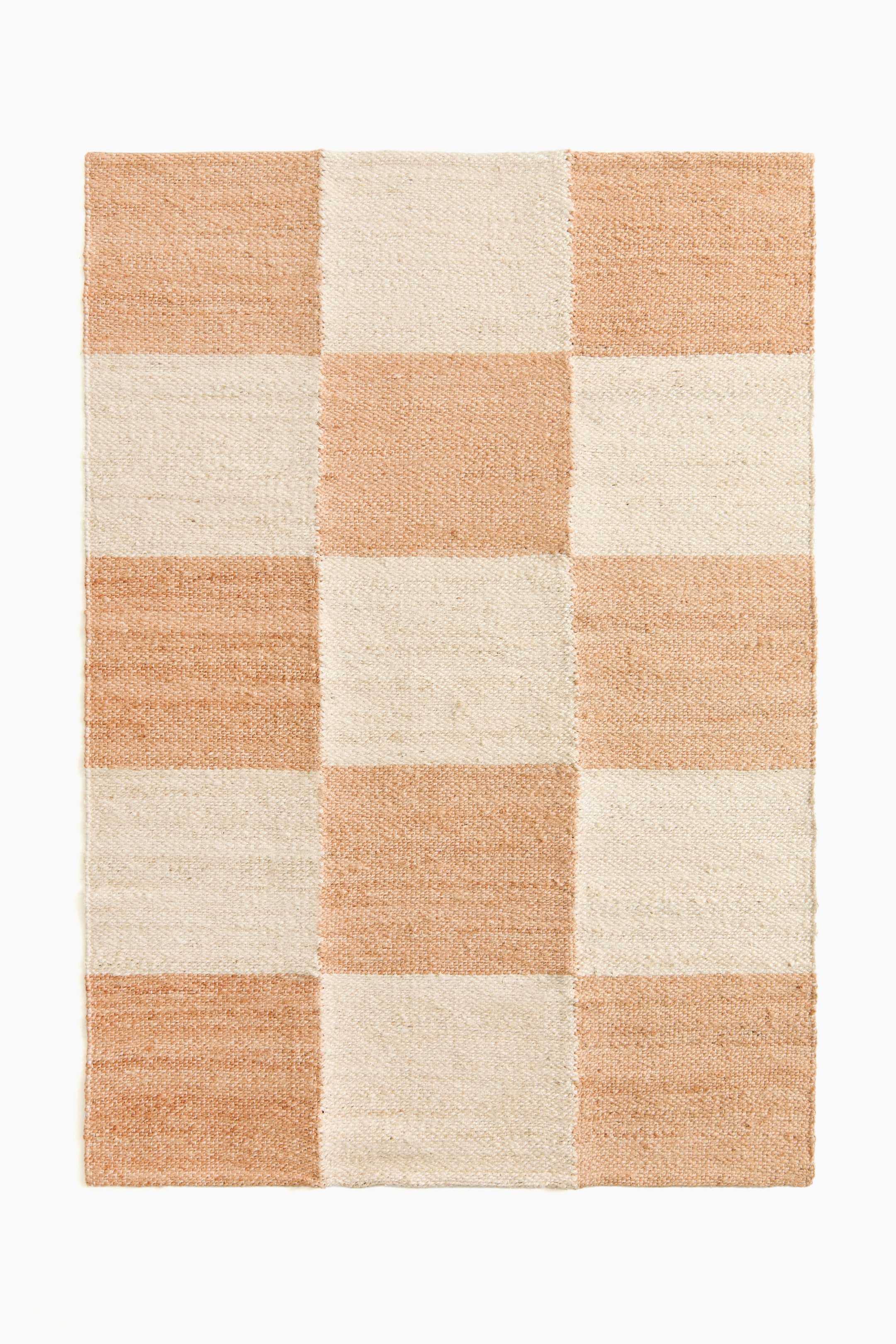 Προβολή μεγαλύτερης εικόνας: Ένα πλεκτό ορθογώνιο χαλί παρουσιάζει σχέδιο σκακιέρας, με εναλλασσόμενα τετράγωνα σε ανοιχτό ροδακινί και εκρού.