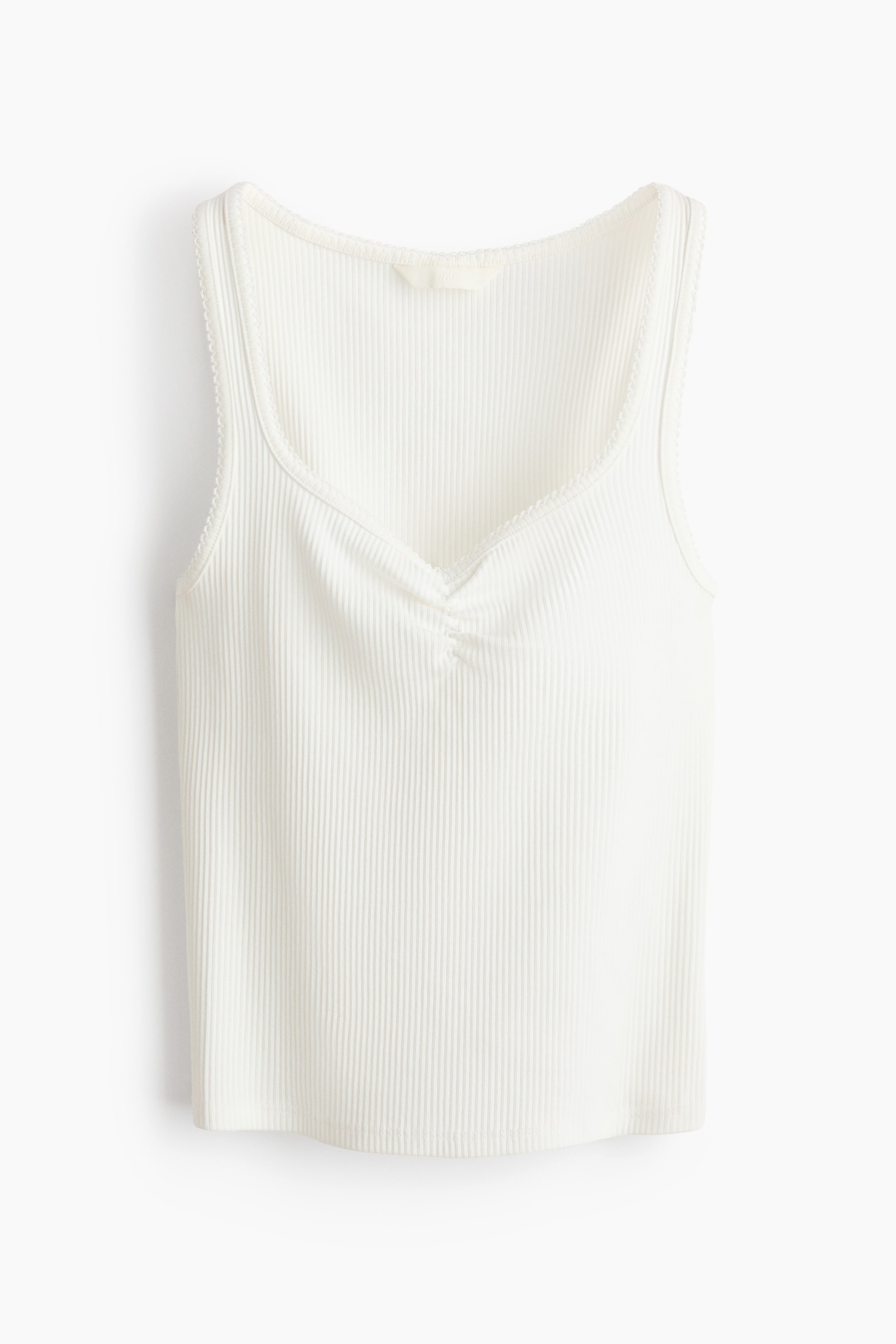 View larger image: "A white ribbed tank top showcases its front, highlighting a V-neckline adorned with central ruching and delicate picot trim along the neckline and armholes."
