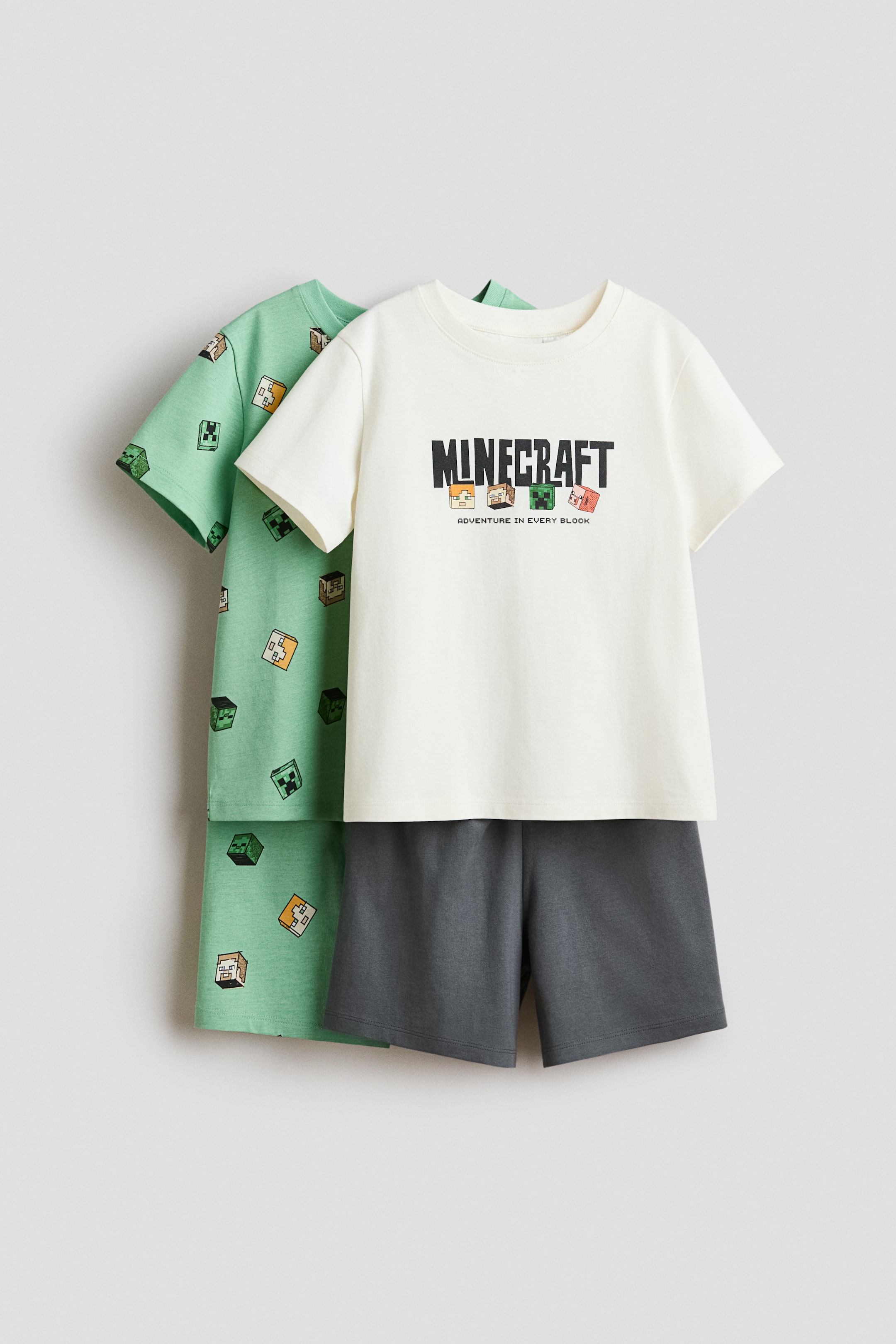 View larger image: Pyjamas come with an off-white cotton jersey T-shirt featuring a Minecraft logo and block characters on the front, complete with a ribbed neckline and dropped shoulders. Paired with dark grey shorts boasting an elasticated waist, a light green cotton jersey T-shirt with an all-over Minecraft block print can be seen layered underneath.