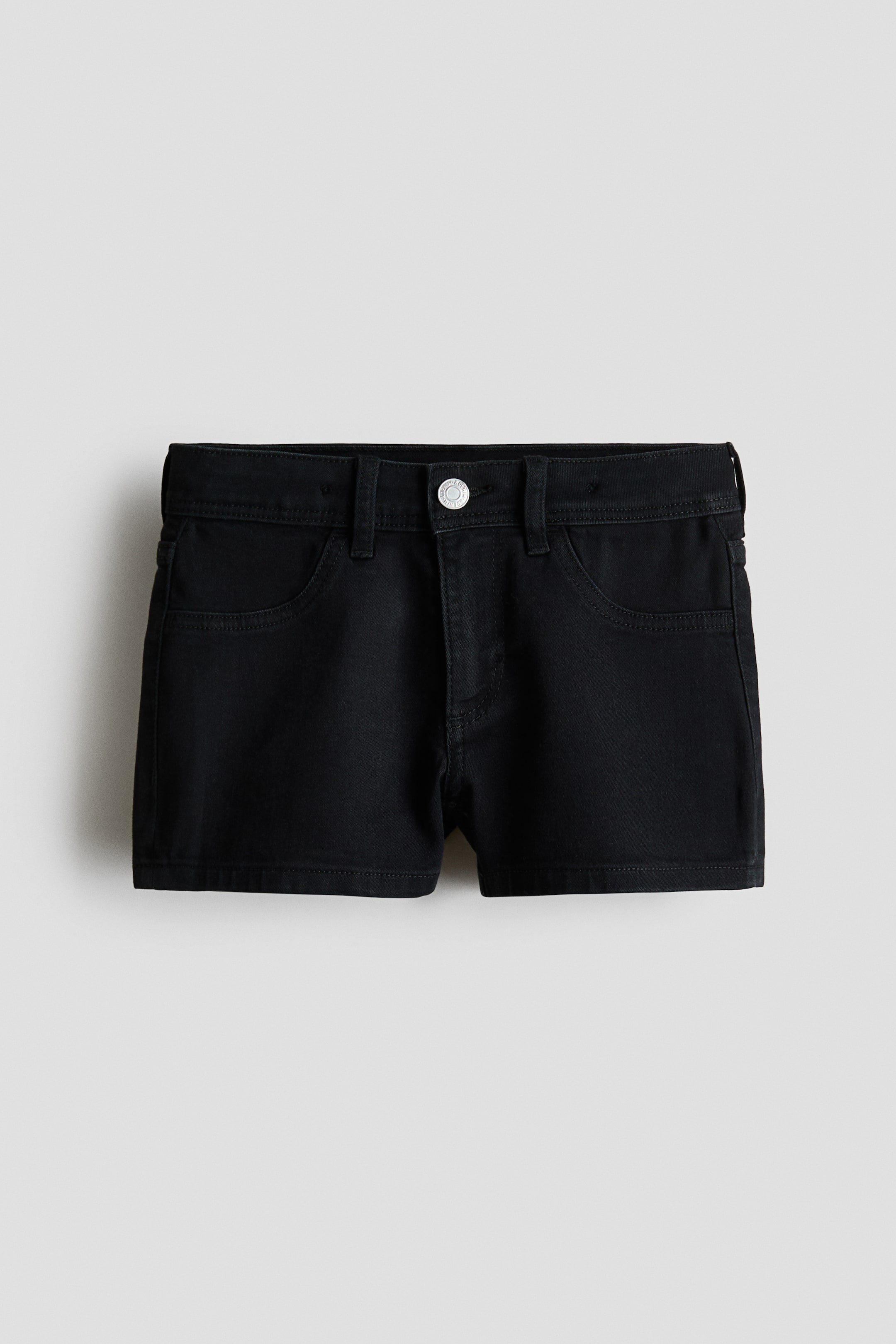 Grösseres Bild ansehen: Schwarze Denim-Shorts in Vorderansicht, ausgestattet mit einem Bund mit Gürtelschlaufen, einem silberfarbenen Knopfverschluss, einem Reißverschluss und zwei geschwungenen Fronttaschen.