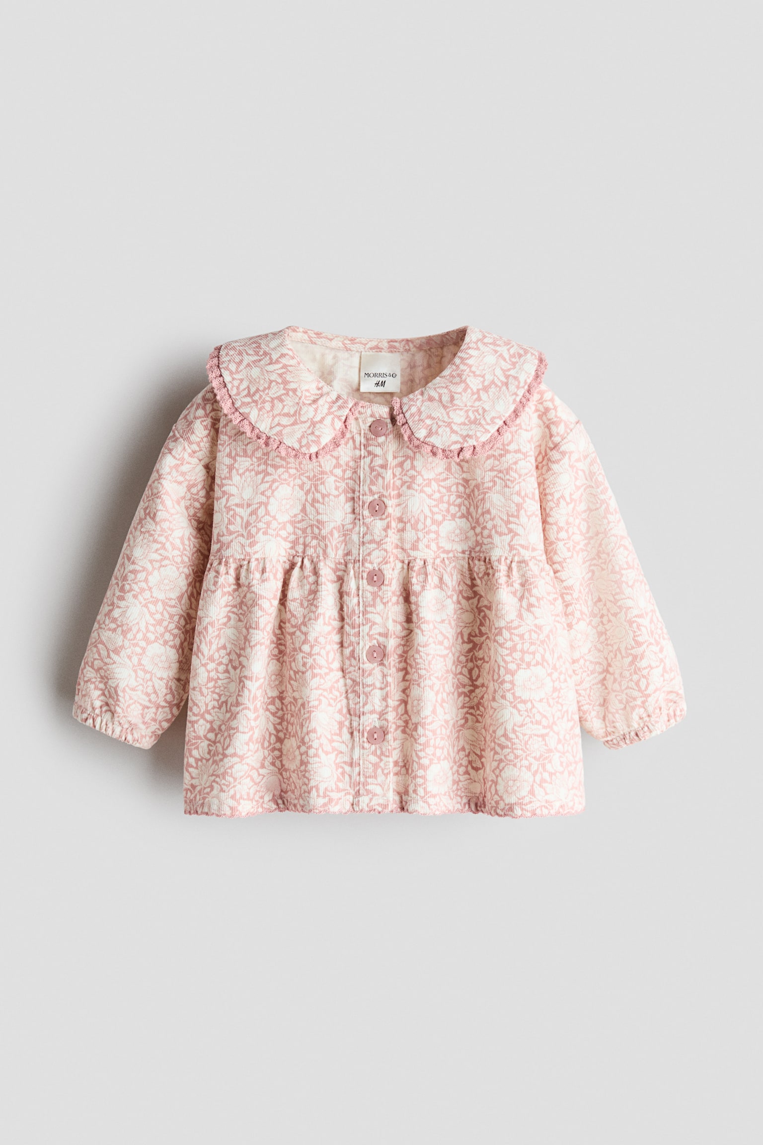 This front-facing view showcases a pink and white floral-patterned corduroy blouse featuring a lace-trimmed Peter Pan collar and matching buttons down the front. The design features a gathered seam above the waist for added volume and long sleeves with elasticated cuffs. - 1