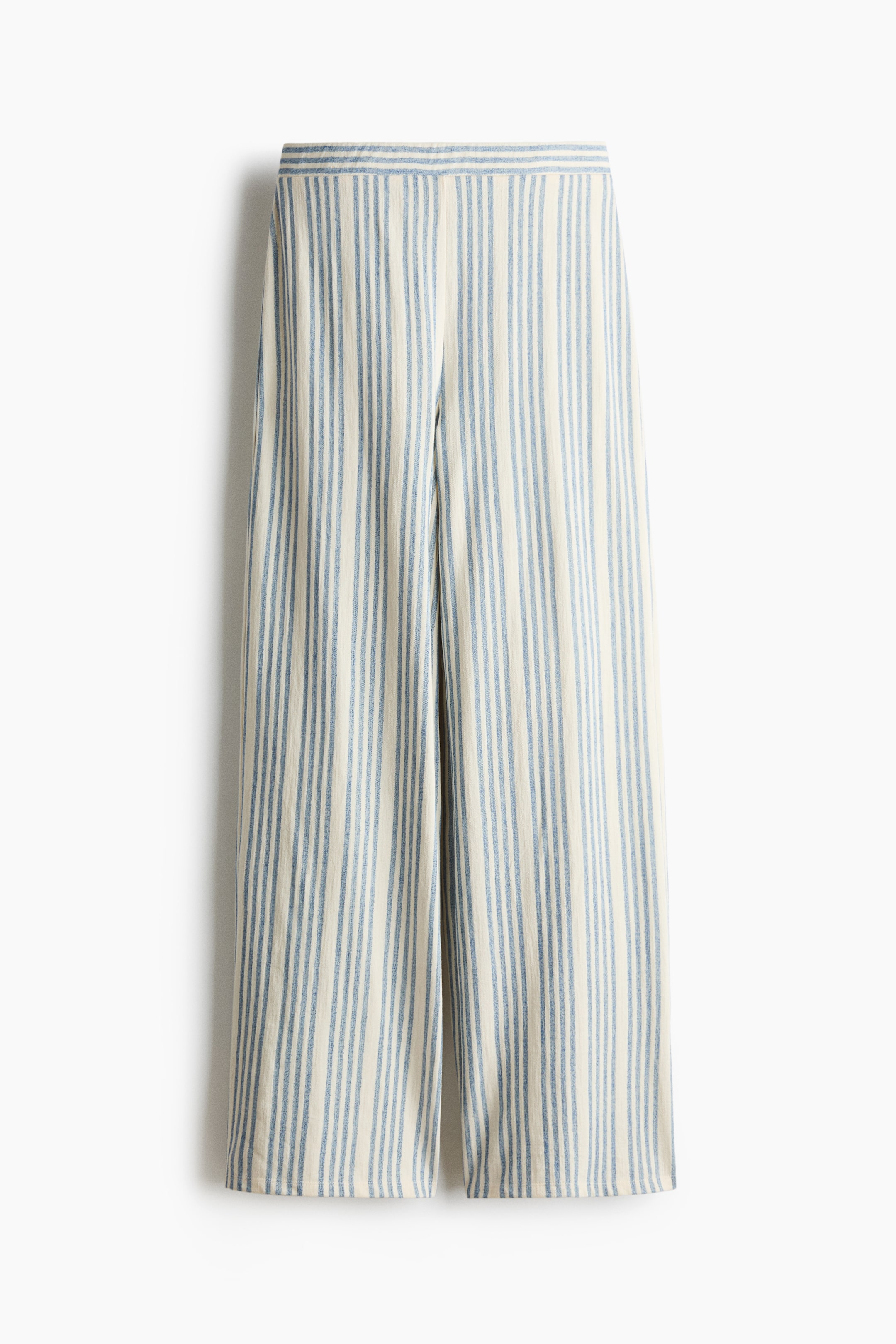 Grösseres Bild ansehen: Relaxed-fit Jerseyhosen werden von vorne präsentiert, mit einem elastischen Bund und weiten Beinen. Sie zeigen ein vertikales Streifenmuster in hellem Creme und Blau.