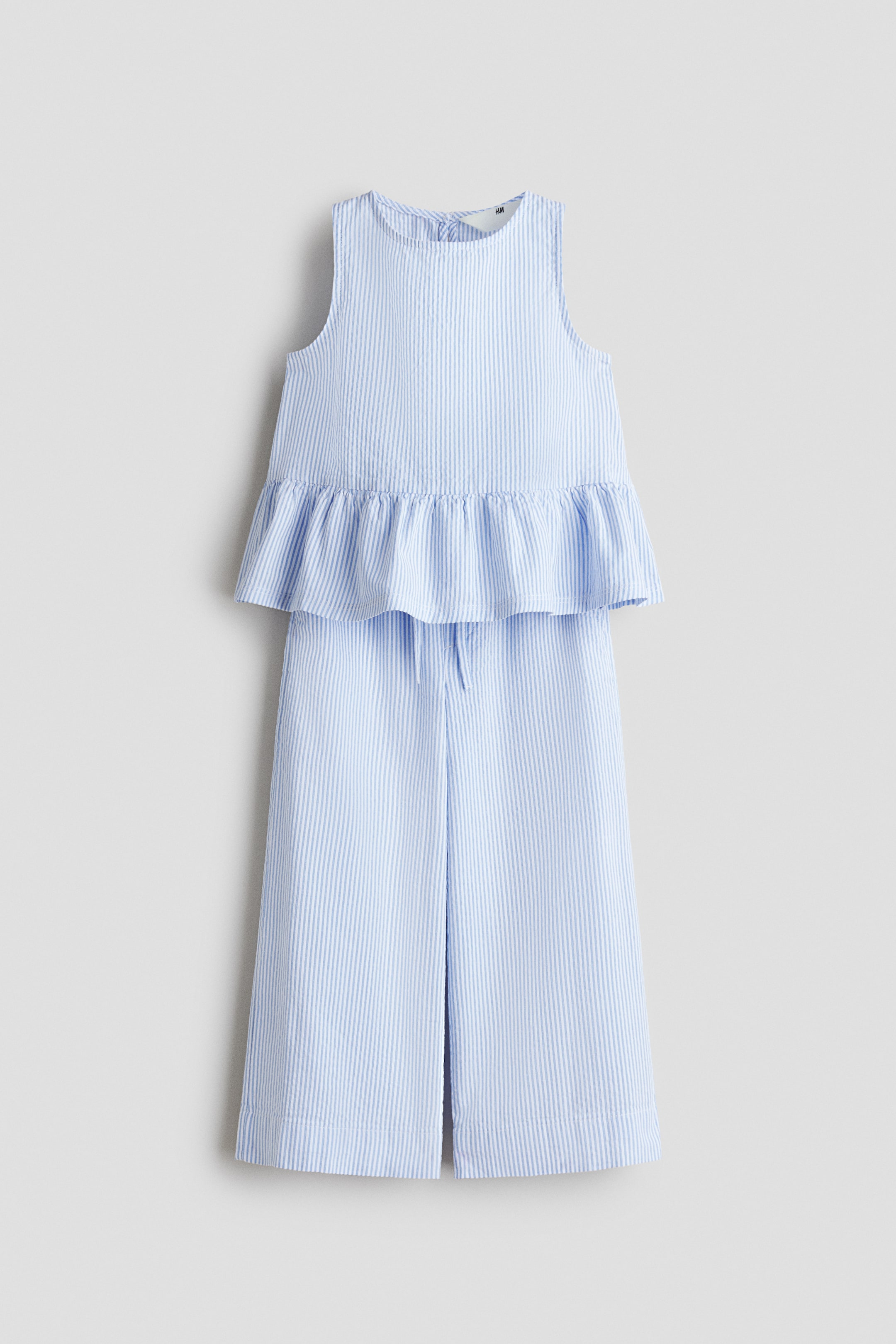 View larger image: A light blue and white seersucker two-piece outfit showcases a sleeveless top with a peplum hem and matching wide-leg cropped pants featuring a drawstring waist.