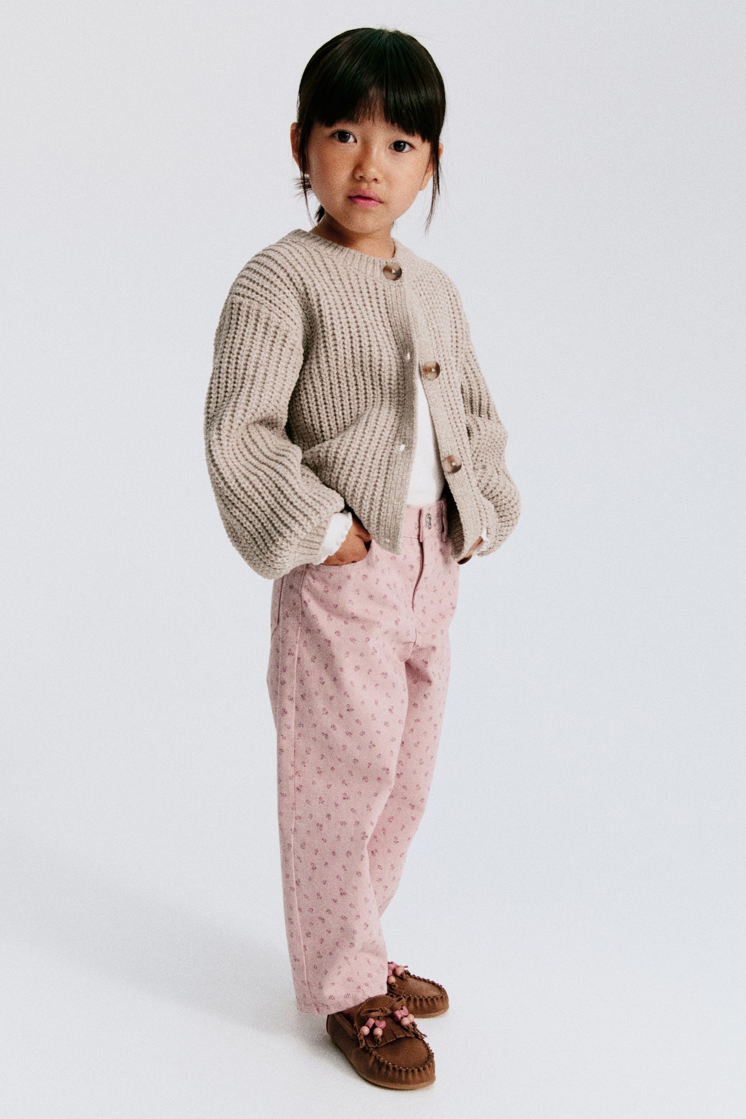 The 5-pocket trousers in cotton twill are displayed from the front, showcasing a pink base colour with a scattered floral pattern. They are crafted with adjustable elastication at the waist, a zip fly with a button, and barrel legs that are finished with darts at the hems. - 1