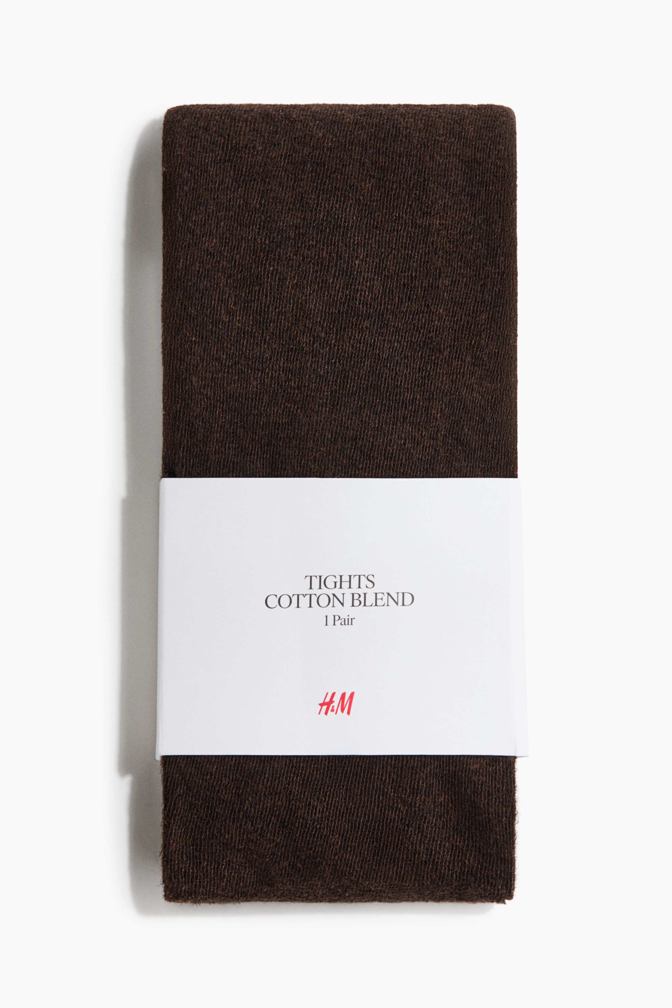 Voir une image plus grande: Une paire de collants en mélange de coton brun foncé est présentée pliée en forme rectangulaire verticale, vue de face. Une bande de papier blanche entoure le centre des collants tricotés et affiche le texte « TIGHTS COTTON BLEND » ainsi qu’un logo rouge.