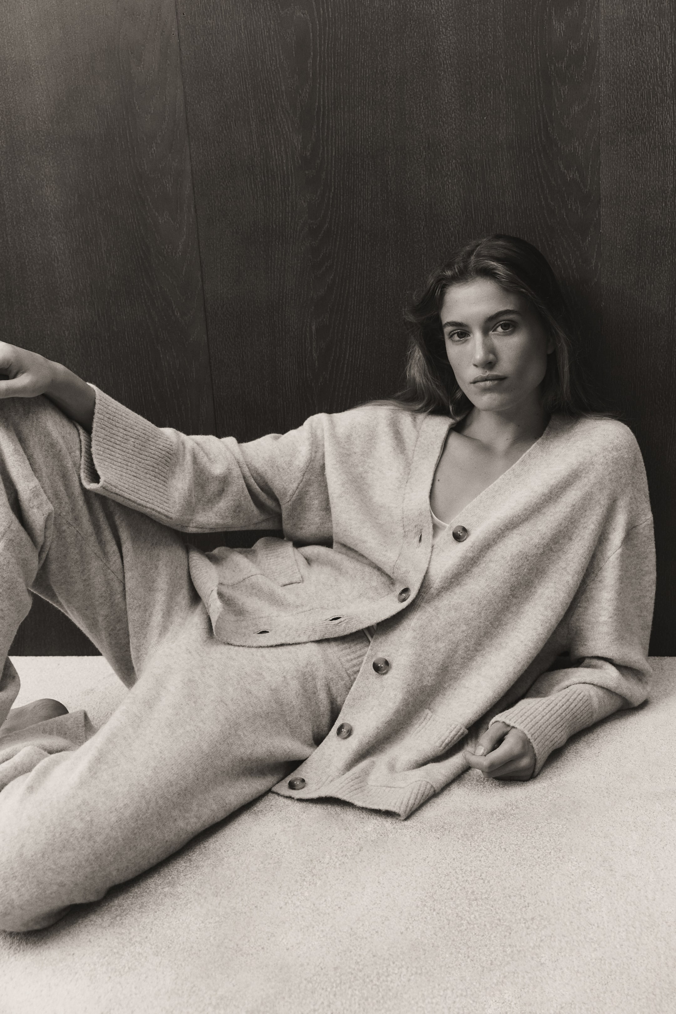 View larger image: A loose-fit knit cardigan is worn from the front, featuring a V-shaped neckline, a button-down front, and dropped shoulders. The cardigan showcases long sleeves with wide ribbed cuffs, open front pockets, and a ribbed hem, and is paired with matching knit trousers.