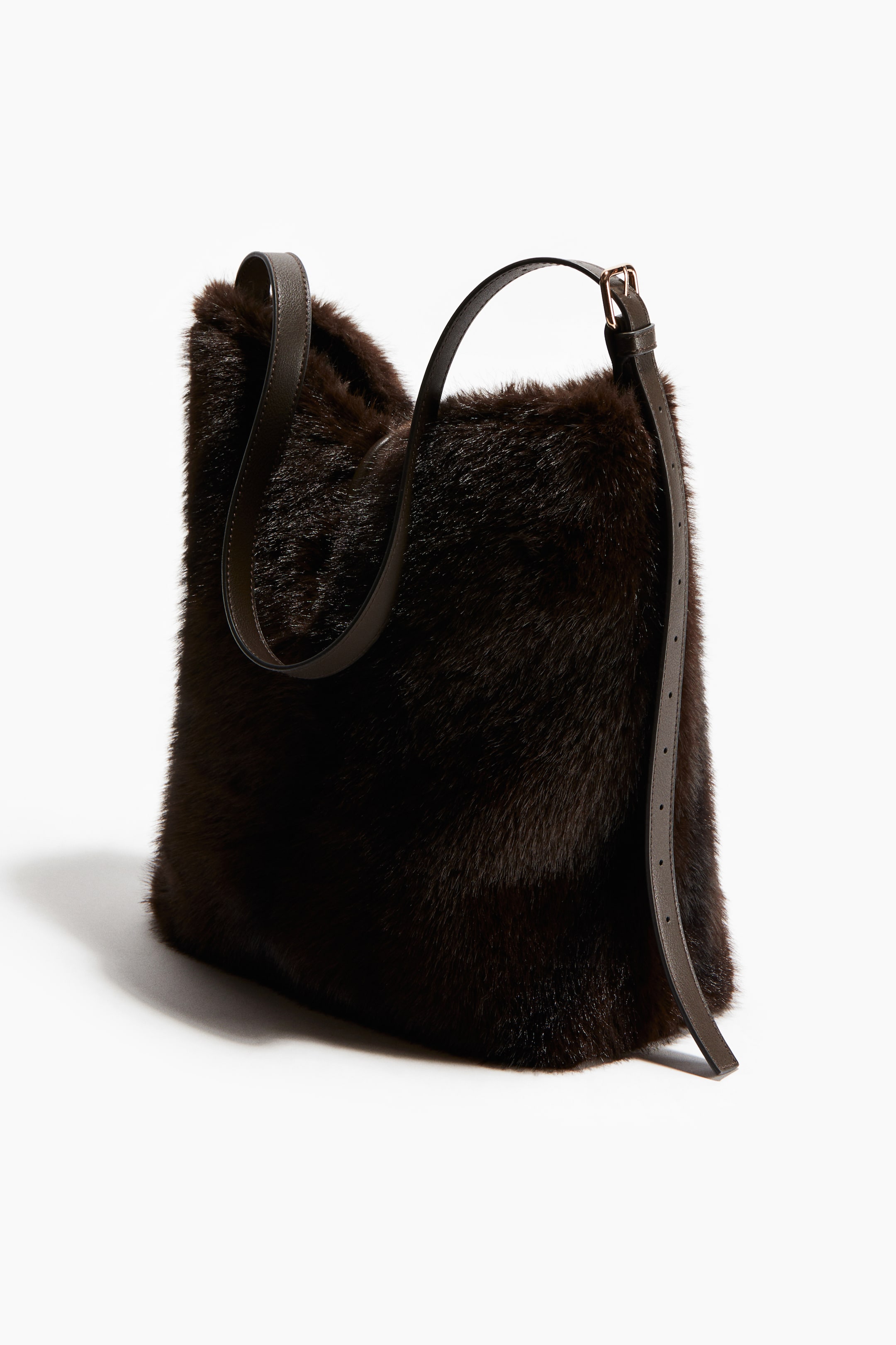 Ver imagen más grande: Un bolso de cubo de piel sintética marrón oscuro presenta una correa de hombro larga y ajustable de color marrón oscuro. La correa se extiende sobre la parte superior y se abrocha en la PARTE DELANTERA del bolso con una hebilla y un lazo de tono dorado visibles.