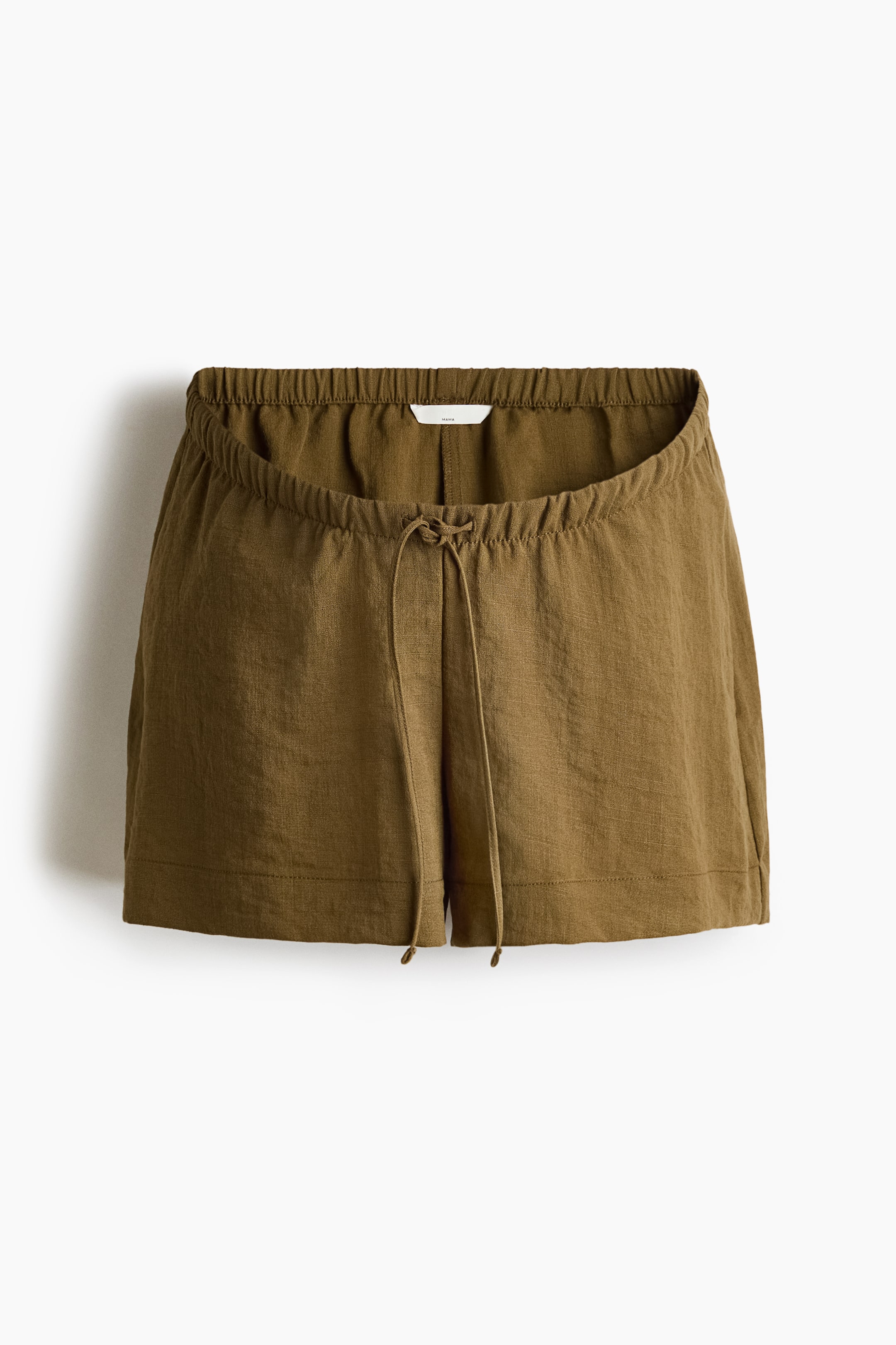 View larger image: The olive green shorts exhibit a relaxed fit from the front, showcasing an elasticized waistband with a drawstring tied at the centre front. The fabric displays a textured appearance.