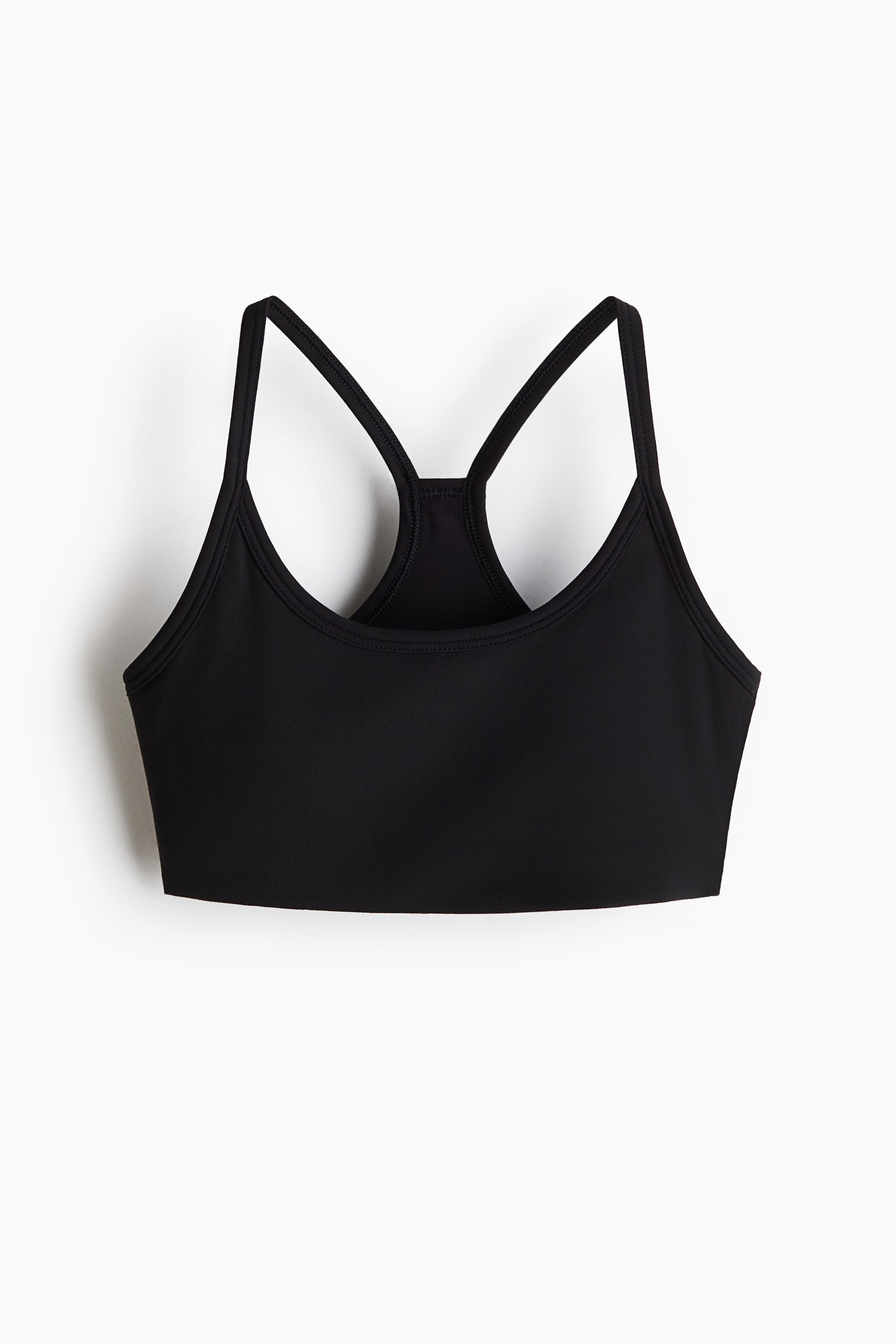 Agrandir l'image: Un soutien-gorge de sport noir est présenté de face, avec de fines bretelles qui se rejoignent en un dos nageur. Il affiche une texture lisse et un ourlet droit.