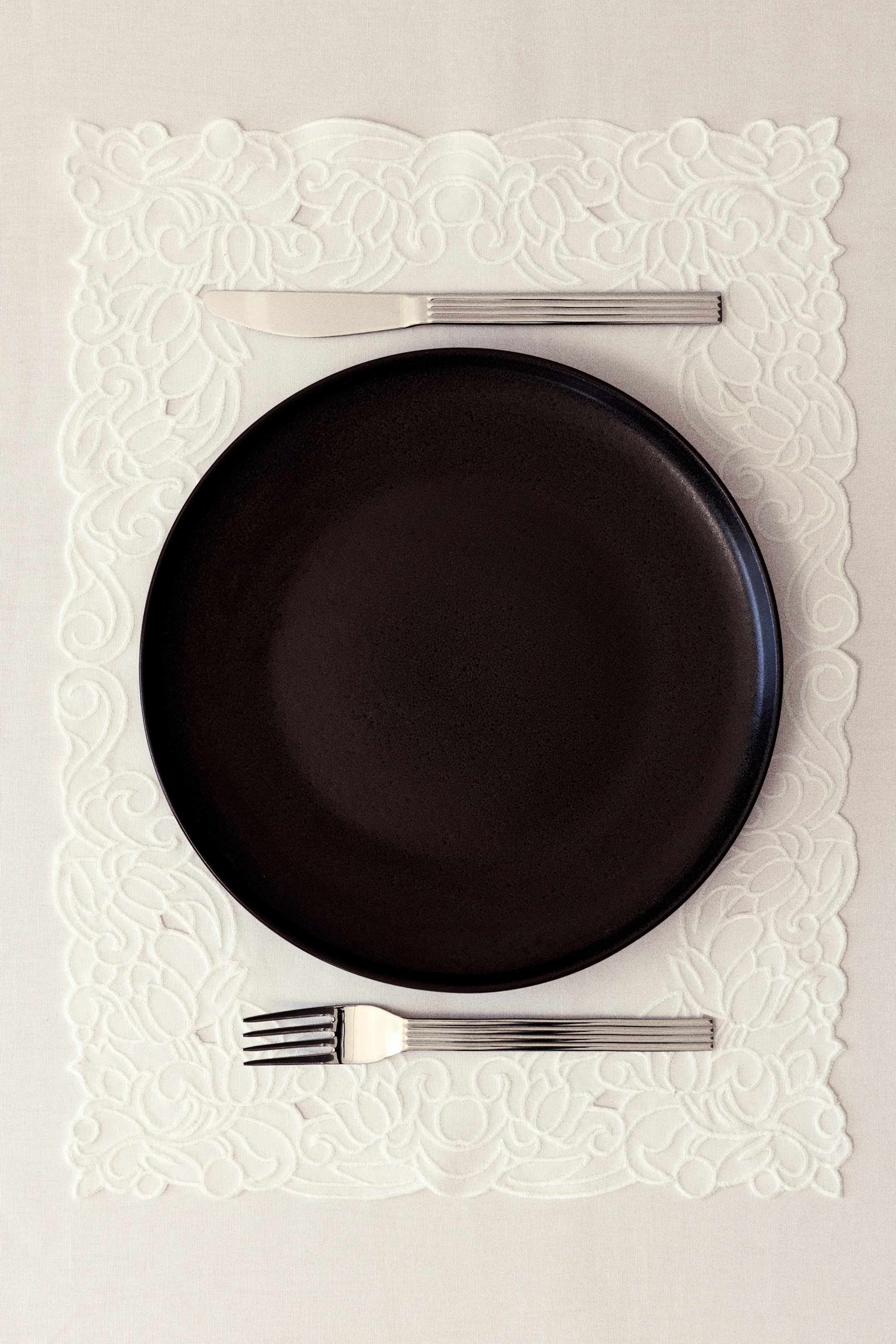 View larger image: A placemat is made of a cotton weave and is detailed with a tone-on-tone embroidered pattern along its edges.