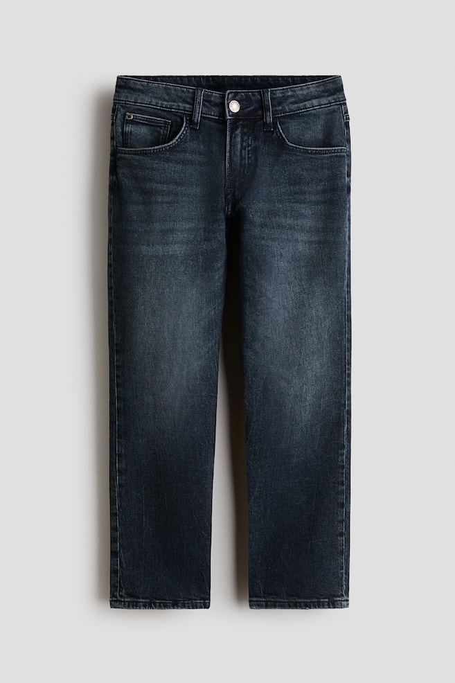 A pair of dark-wash, five-pocket denim jeans is displayed from the front, featuring a relaxed fit with tapered legs. The jeans show subtle fading along the thighs and knees, and include a waistband with belt loops and a metal button fastening. - 1